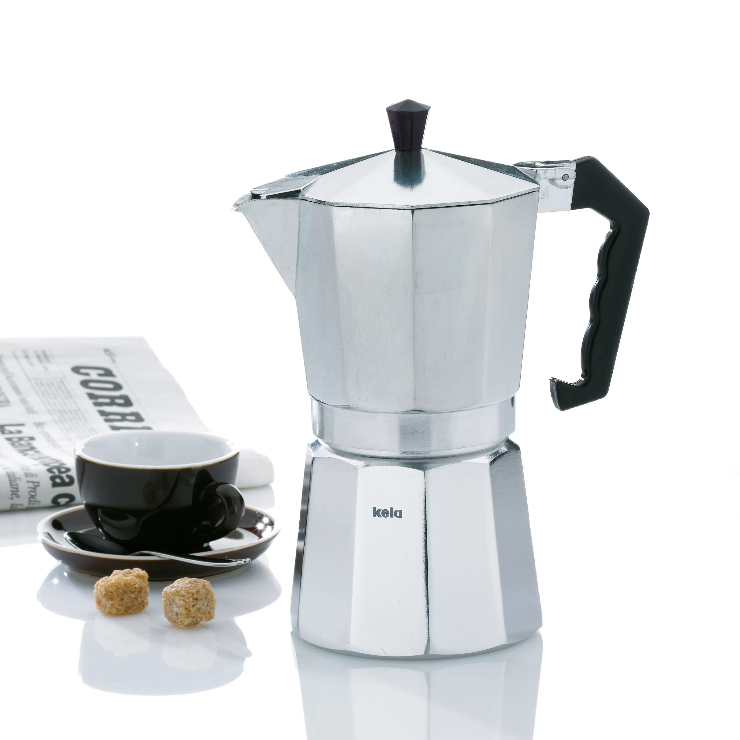 Kela Moka-Kanne Espressokocher Aluminium Kela Moka-Kanne aus Aluminium mit schwarzem Griff neben Espressotasse, Zeitung und Zuckerstücken