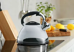 Flötenkessel Edelstahl - Wasserkessel mit Induktion für moderne Küchen Moderner Flötenkessel aus Edelstahl mit schwarzem Griff auf Induktionskochfeld in heller Küche
