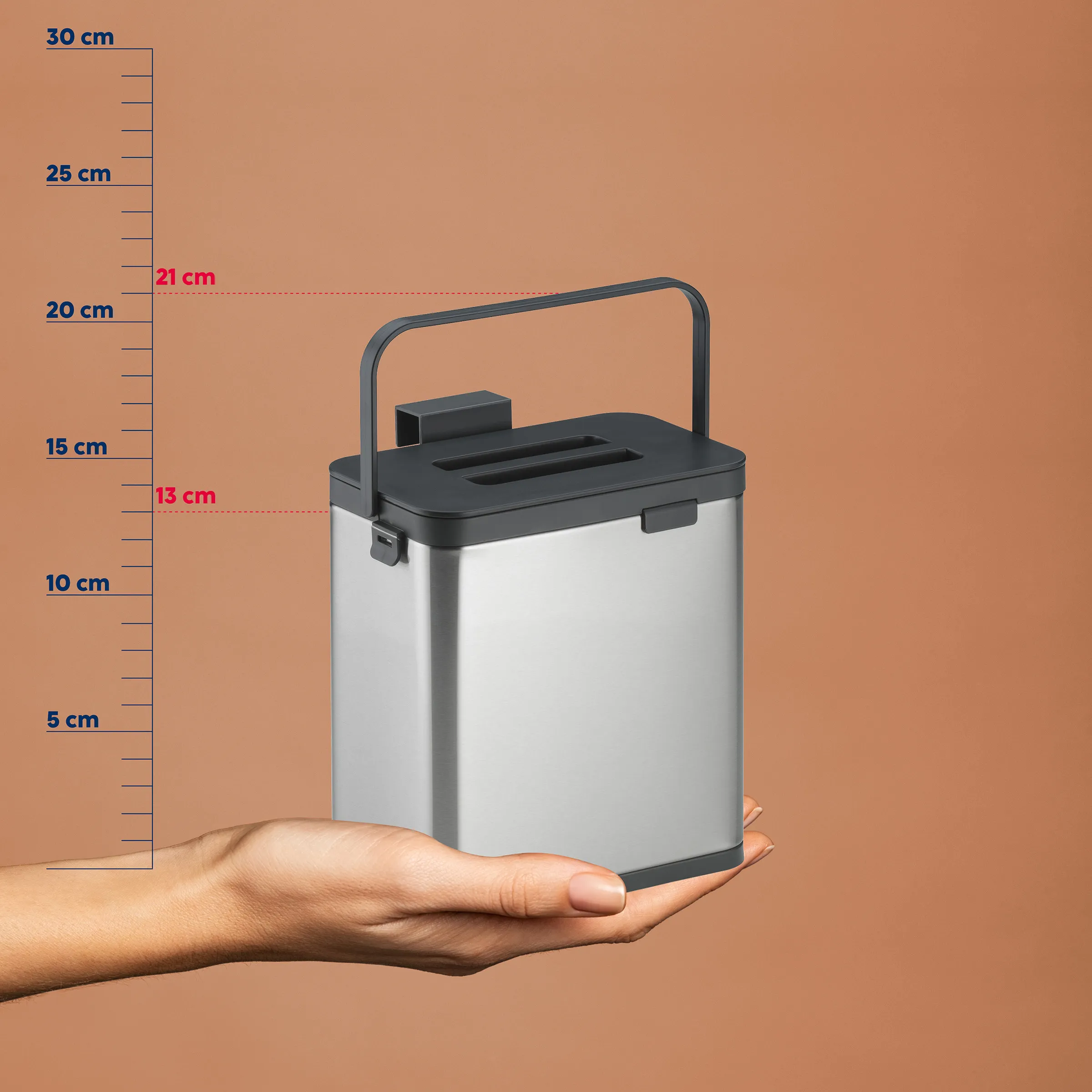 Kompakte tragbare Kompostierbox mit schwarzem Deckel und Griff, auf Maßstab ca. 13 cm Höhe, in Hand gehalten
