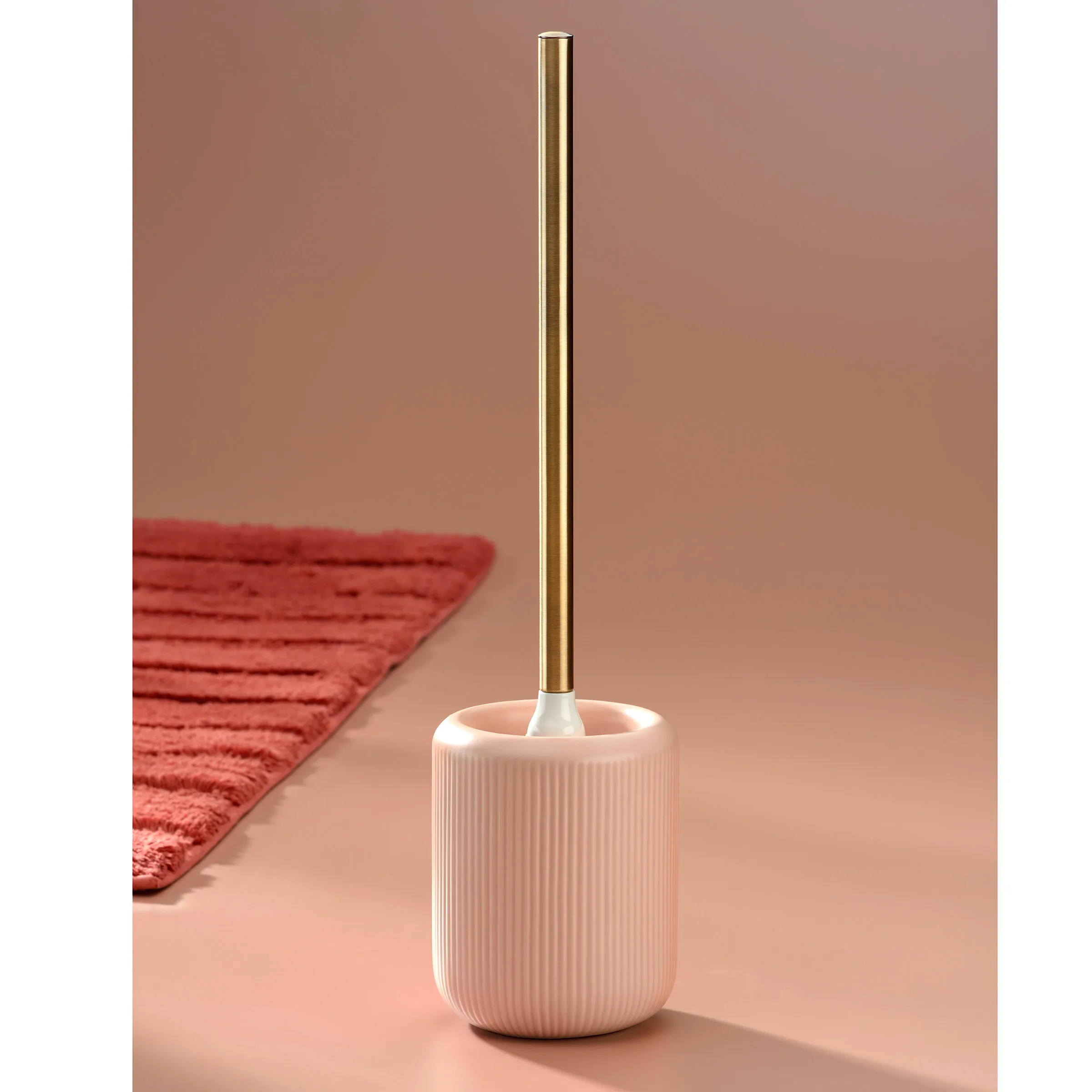 Moderne Toilettenbürste Keramik mit Messinghalter Modische Toilettenbürste aus Keramik mit gerippter Oberfläche und Messinghalter auf beigem Hintergrund neben rotem Teppich