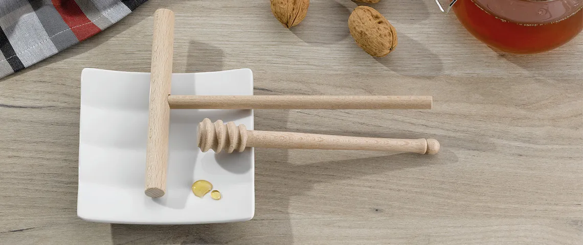 Honig Rührstab und Schöpflöffel Set aus Holz Holzenes Honiglöffel-Set mit Rührstab auf weißem Teller mit Honigtropen auf Holztisch