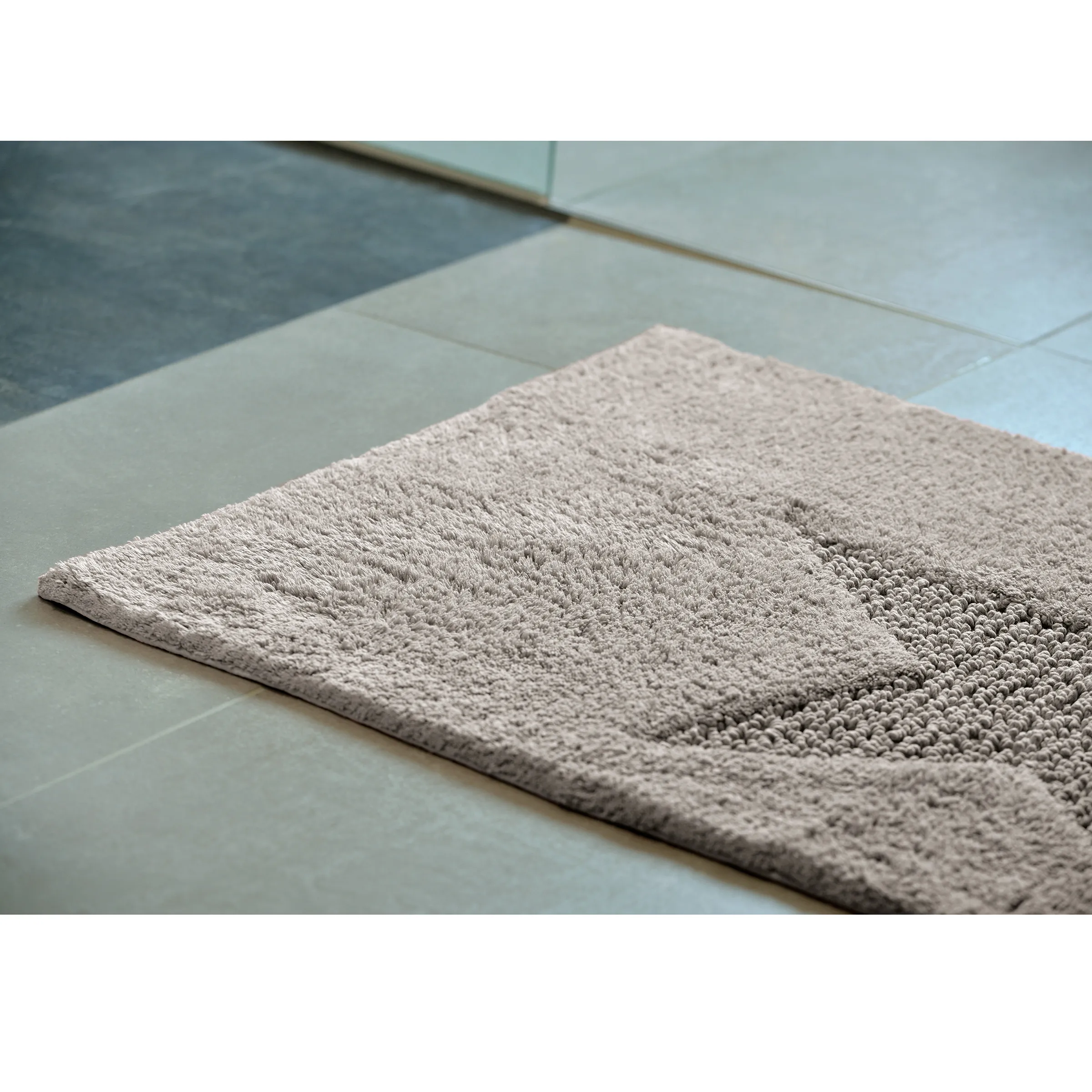 Badteppich beige - rutschfester Badezimmerteppich Beiger Badteppich auf hellen Bodenfliesen mit strukturierter Oberfläche und Flauschrand