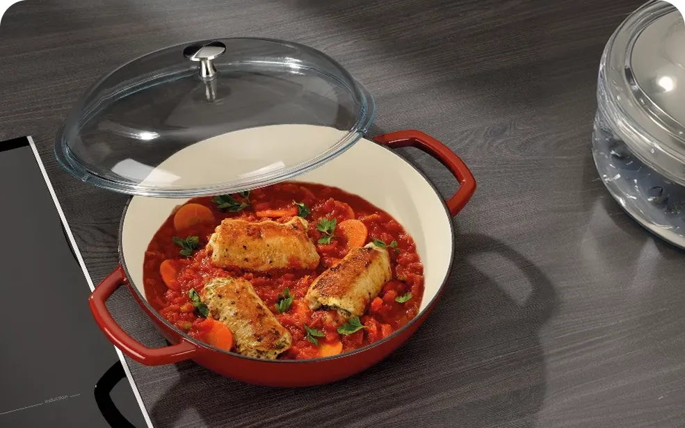 Cast Iron Pot with Glass Lid - Fish Fillets in Tomato Sauce Preparation Red cast iron pot with fish fillets in tomato sauce on induction cooktop with glass lid beside it