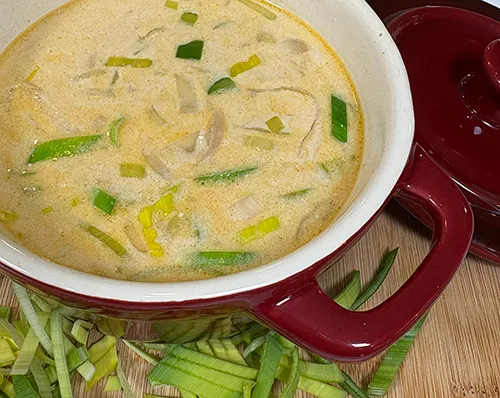 Lauchsuppe Rezept - Cremige Suppe mit frischem Lauch im Gusseisentopf Cremige Lauchsuppe mit frischen Lauchstücken in rotem Gusseisentopf auf Holzbrett
