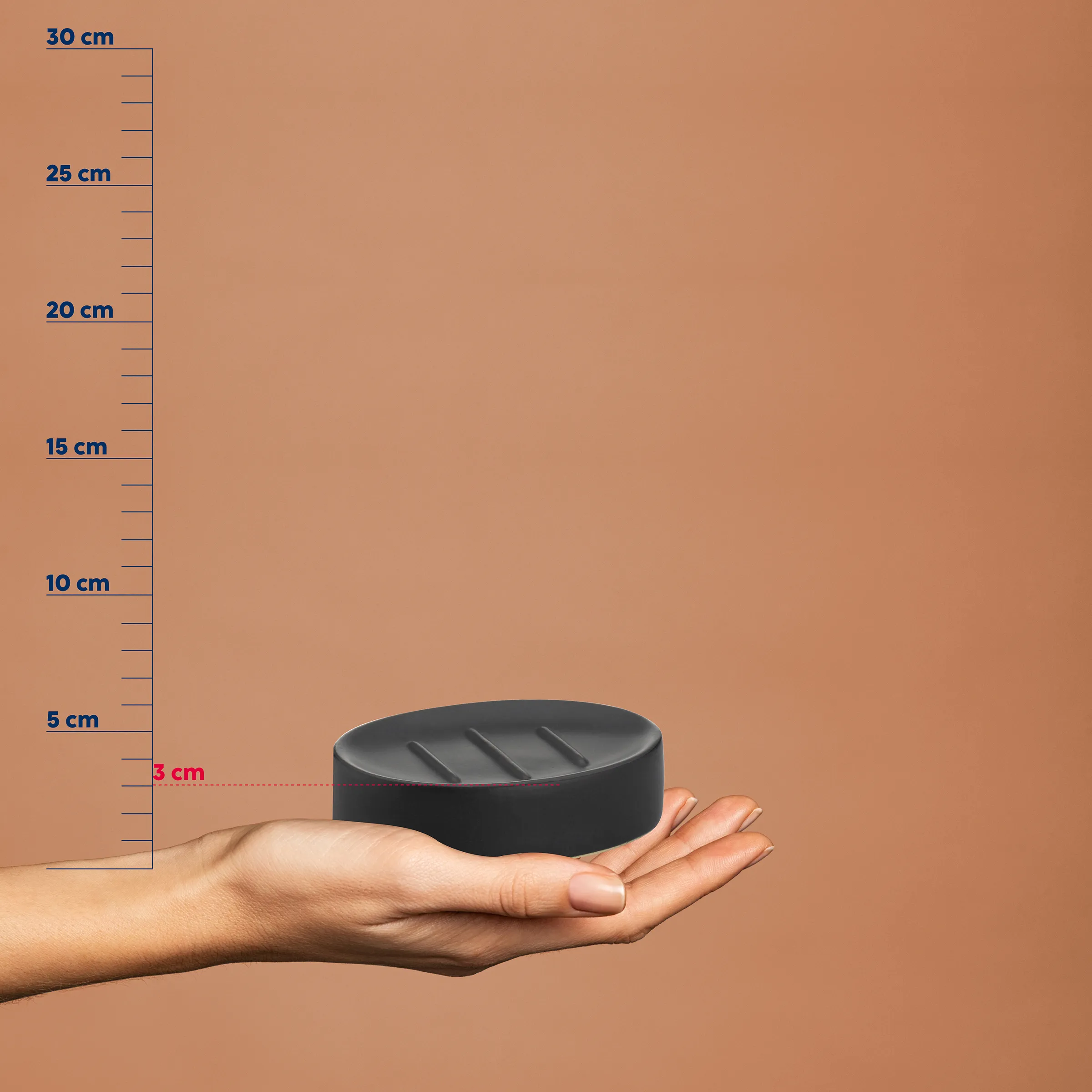 Seifenschale oval schwarz - kompakte Badezimmer Accessoires Schwarze ovale Seifenschale mit Rillen in einer Hand, neben einer Messskala von 0-30 cm. Höhe etwa 3 cm.