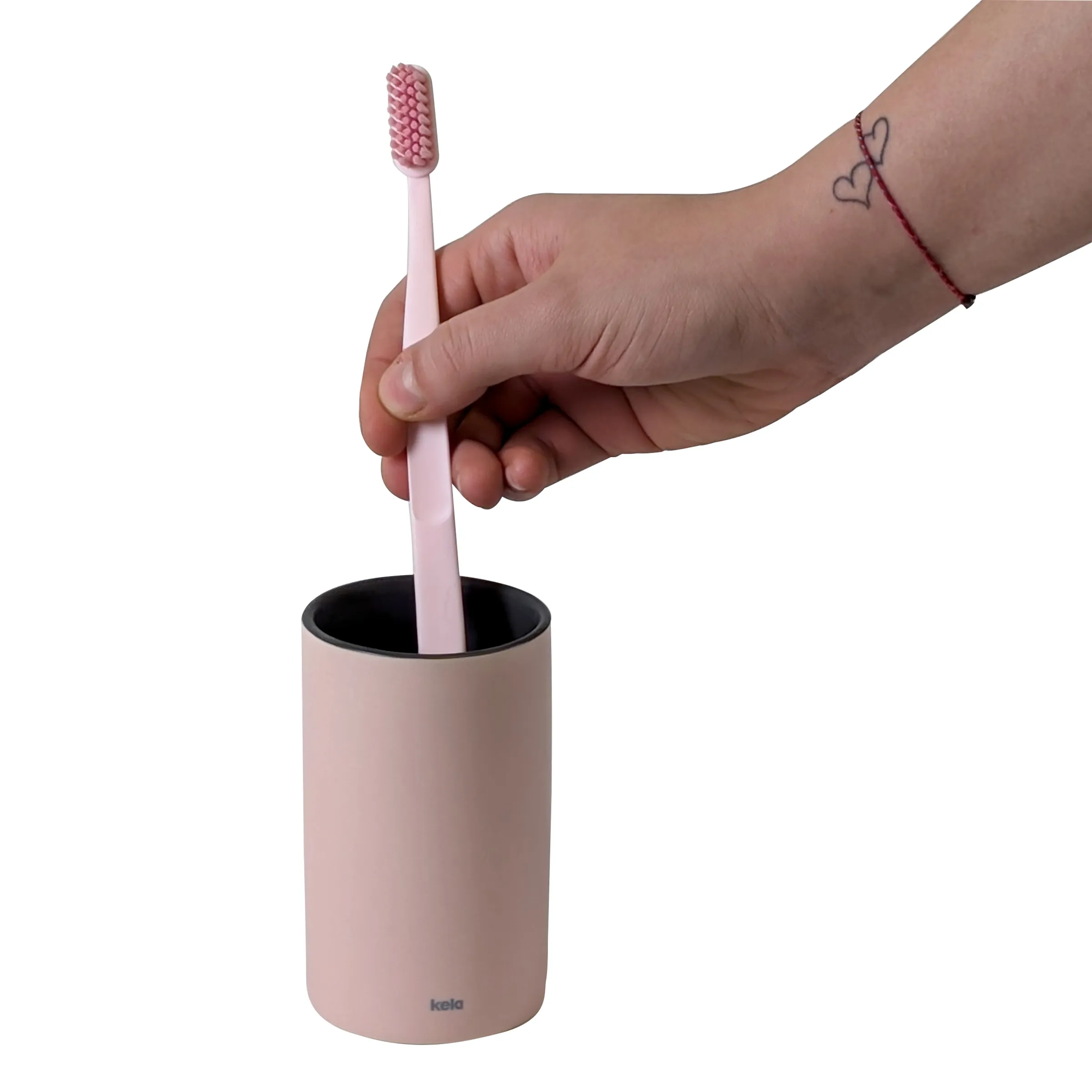 Rosa Zahnbürste mit Halter Set - Badezimmer Zahnpflege Organizer Hand mit rotem Armband legt rosa Zahnbürste in rosa Zahnbürstenhalter auf weißem Hintergrund