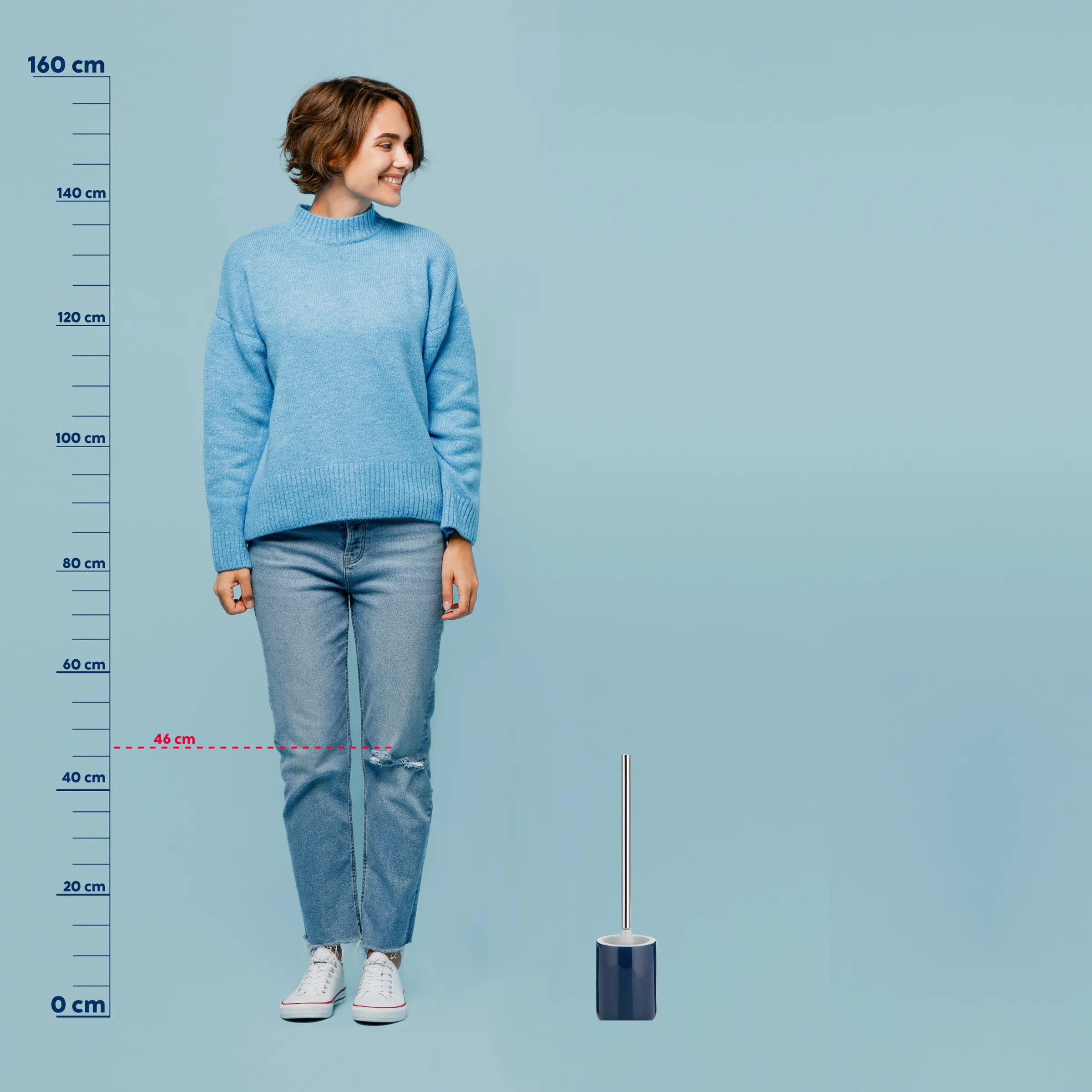 Größenvergleich: Frau mit Toilettenbürste und Messskala Frau in hellblauem Rollkragenpullover und zerrissener Jeans mit Größenangaben von 0-160 cm neben einer Toilettenbürste.