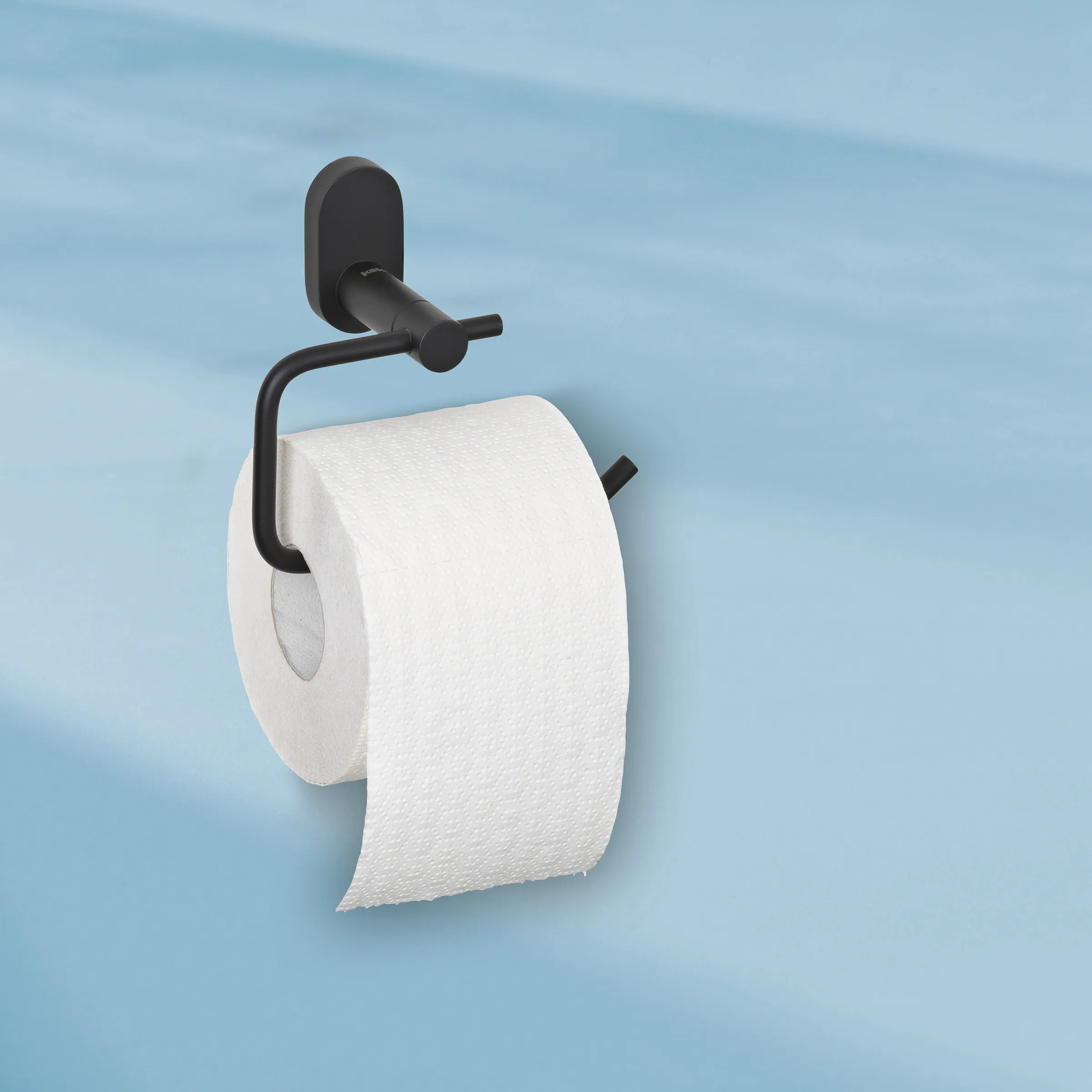 Schwarzer Toilettenpapierhalter an blauer Wand mit weißer Toilettenpapierrolle