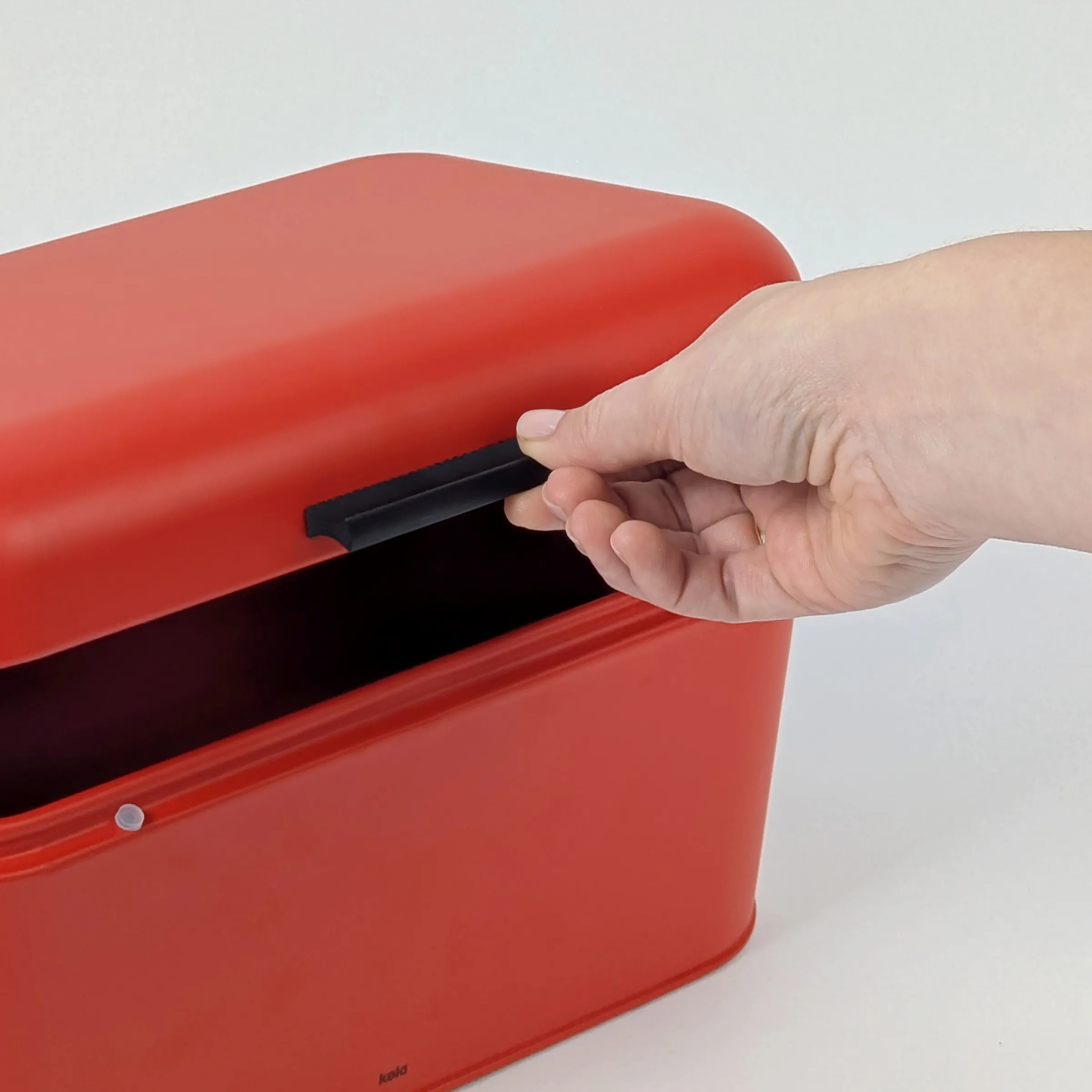 Aufbewahrungsbox mit Klappdeckel öffnen - Stapelbarer Kunststoffbehälter Hand öffnet roten Aufbewahrungsbehälter mit schwarzem Klappdeckel