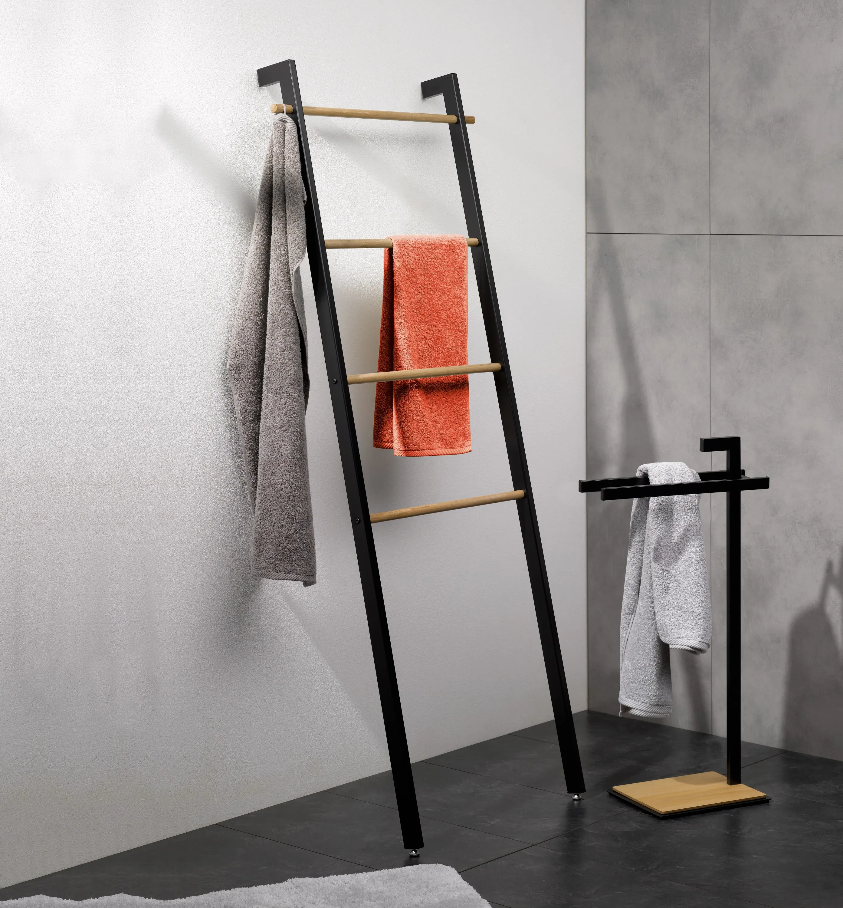 Handtuchleiter Badezimmer - Modernes Design Moderne Handtuchleiter aus schwarzem Metall mit Holzsprossen in minimalistischem Badezimmer. Graue und orangefarbene Handtücher hängend.