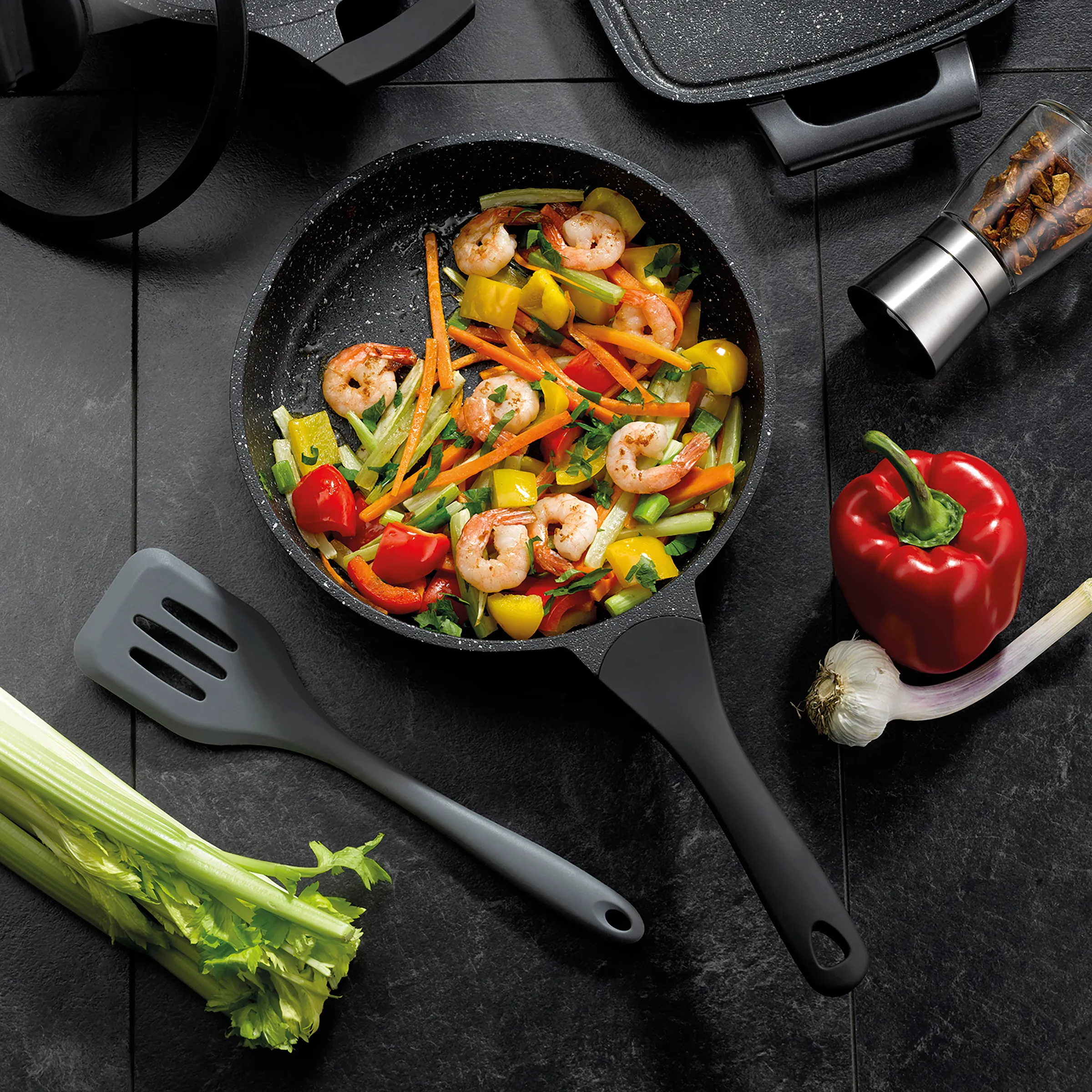 Garnelen Pfanne mit Gemüse - schnelle Wok-Rezept Schwarze Pfanne mit gebratenen Garnelen und buntem Gemüse wie Paprika, Zucchini und Karotten auf dunklem Untergrund