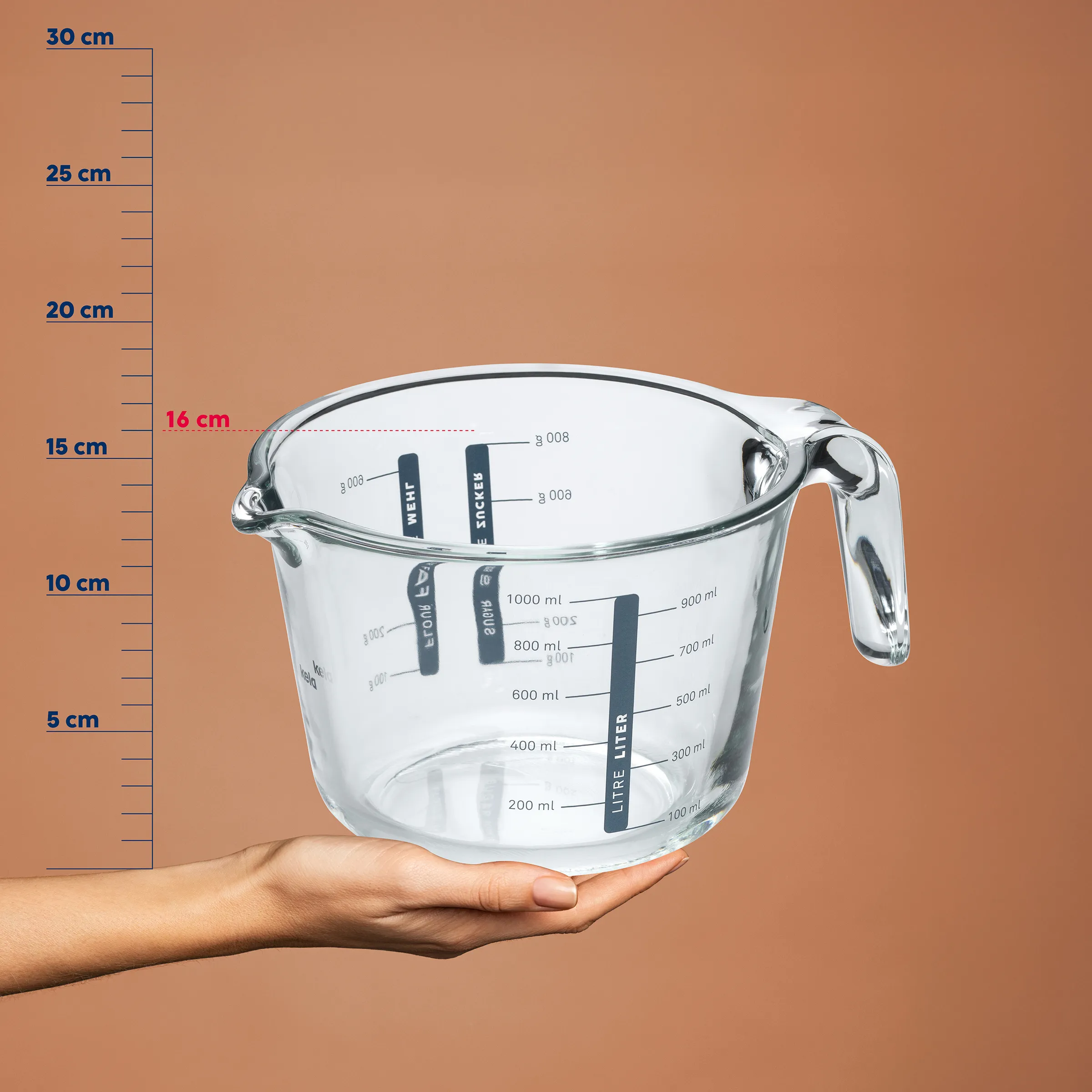 Glaskrug Messbecher Liter Küche Glaskrug mit Messskalen und Griff, in einer Hand gehalten, vor Höhenreferenzskala