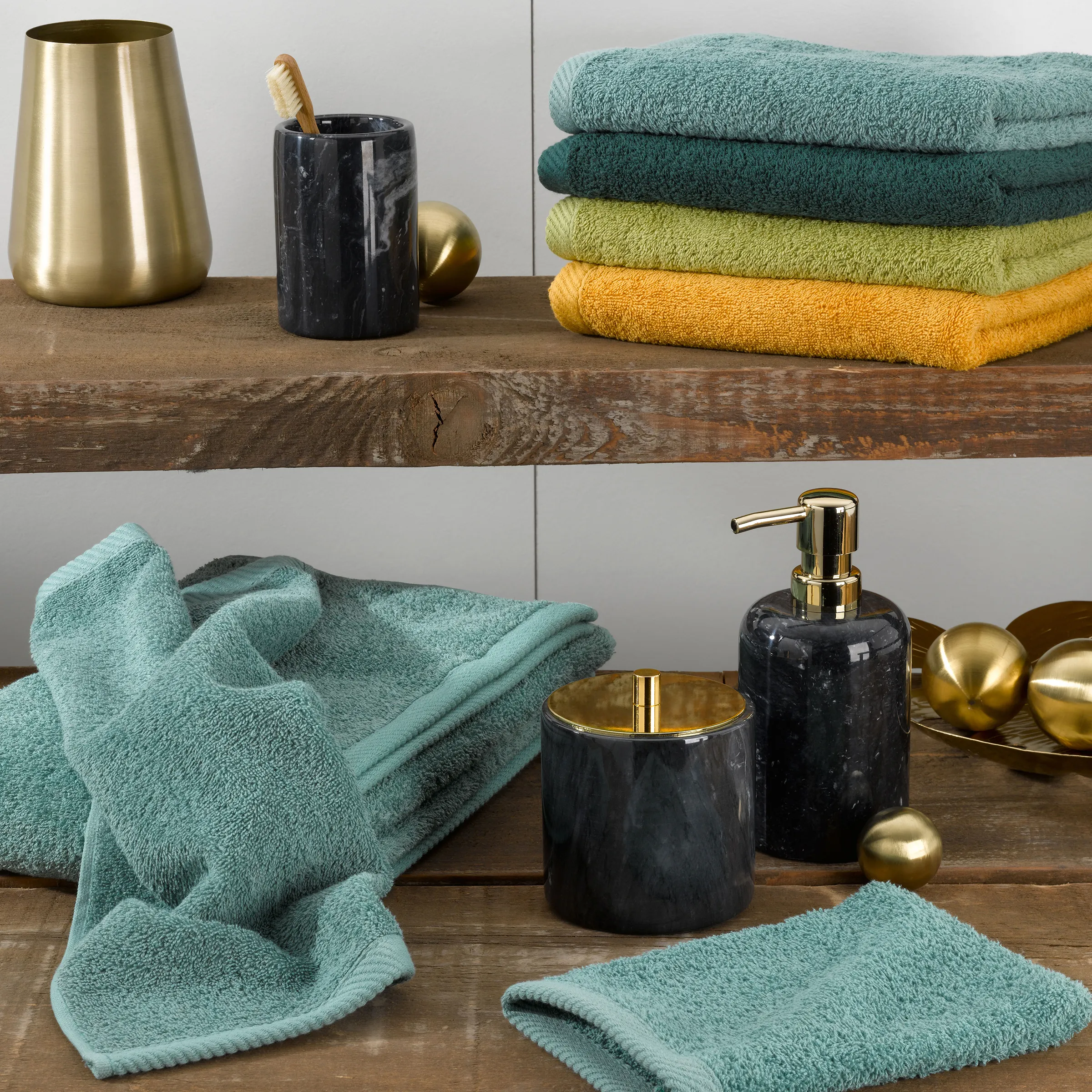 Luxus Badezimmer Accessoires Set mit Marmor und Gold Badezimmer-Accessoires Set mit Handtüchern, schwarzem Marmor-Seifenspender, Zahnbürsten-Behälter und goldenen Deko-Kugeln auf Holzregal