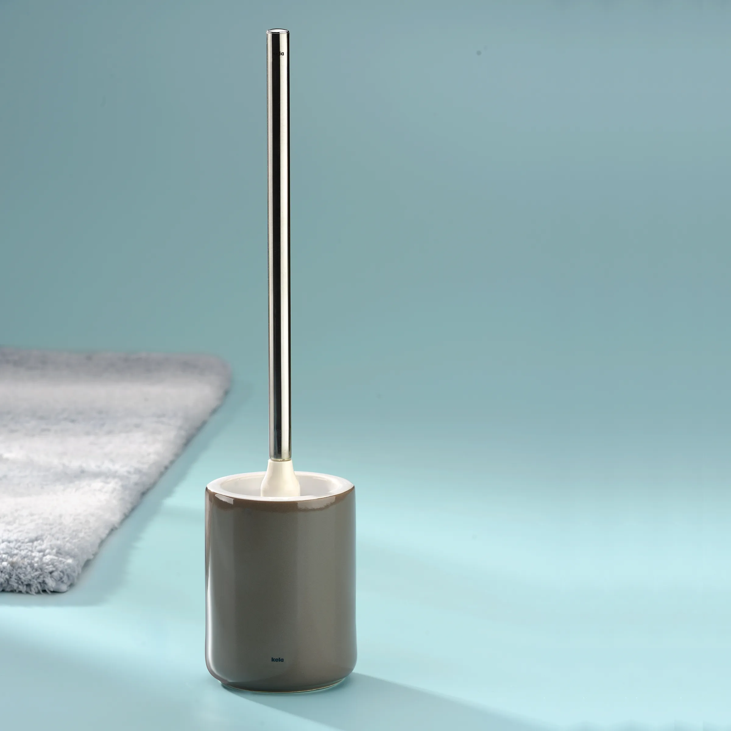 Moderne Toilettenbürste grau mit Edelstahl-Stiel Graue Toilettenbürste mit metallischem Stiel und weißem Bürstenkopf auf blauem Hintergrund neben Handtuch