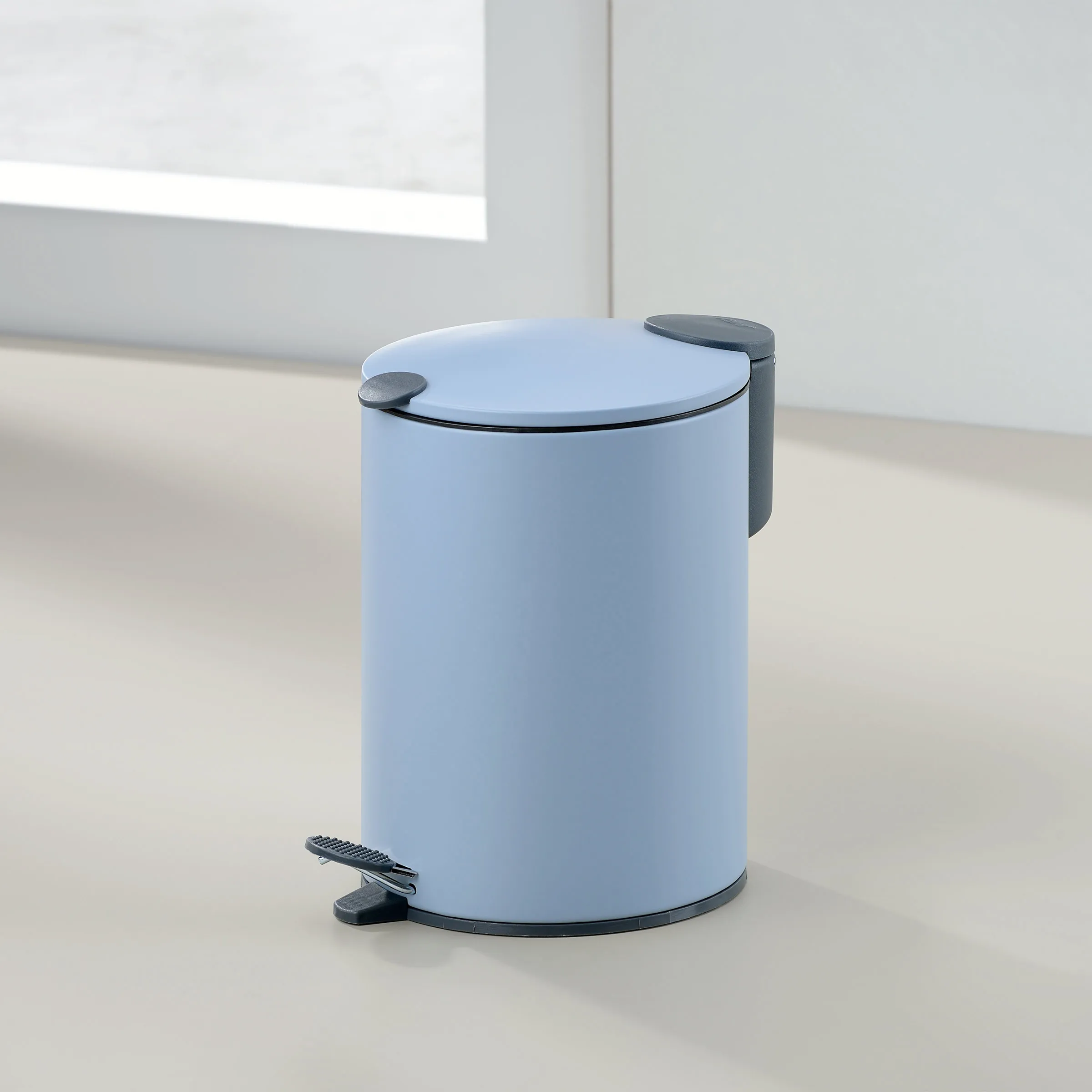 Tretmülleimer hellblau mit Pedal - moderner Abfalleimer für Bad und Küche Hellblauer Tretmülleimer mit dunkelgrauem Fußpedal und Deckel in minimalistischem Badezimmer