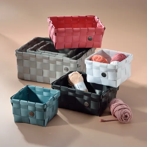 Mehrfarbige Aufbewahrungskörbe aus Kunststoff in Rosa, Grau, Weiß, Schwarz und Blau mit gestrickten Wollelementen