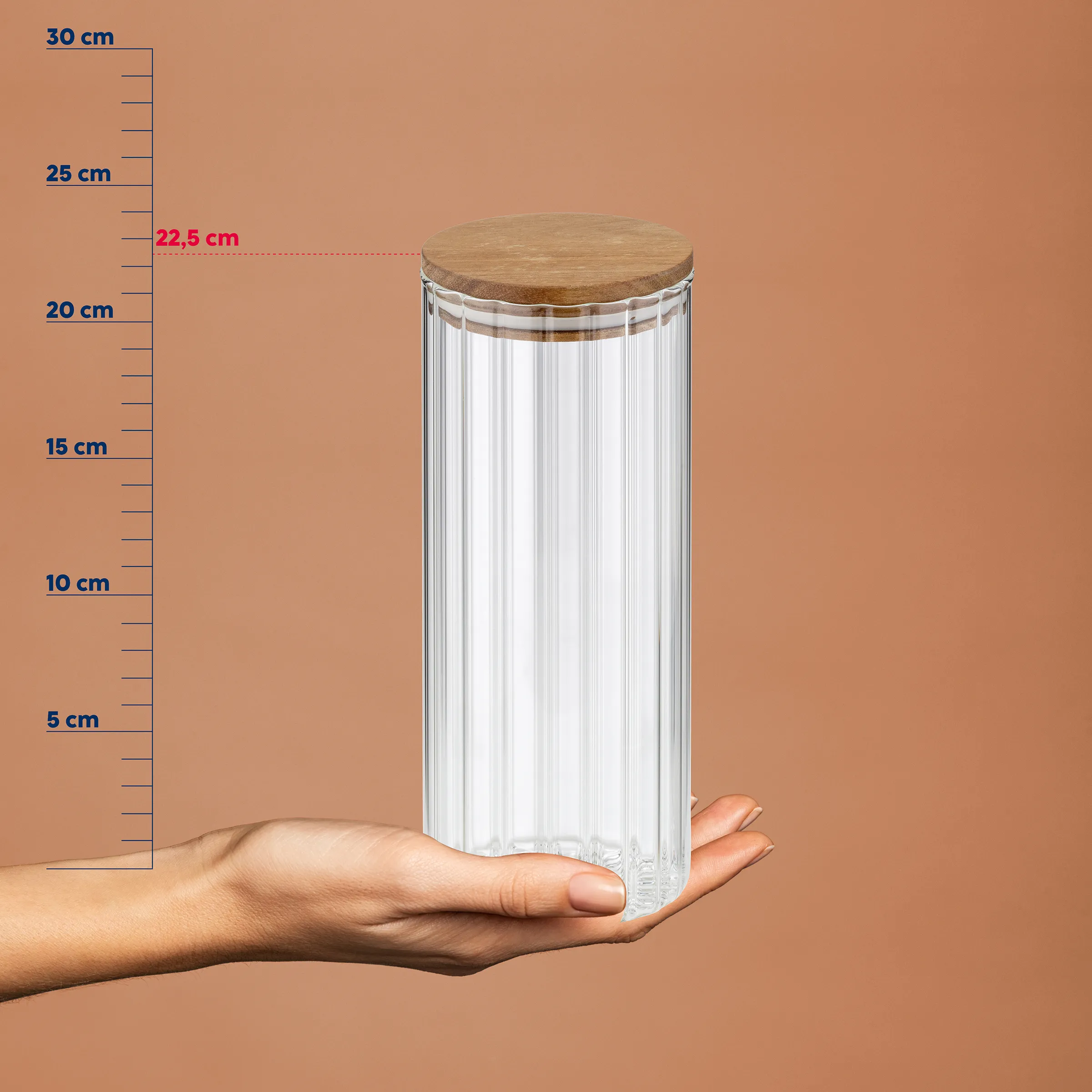 Vorratsglas mit Holzdeckel 22,5 cm - Aufbewahrungsbehälter Küche Hand hält Vorratsglas aus Glas mit Holzdeckel vor Messskala, Höhe 22,5 cm