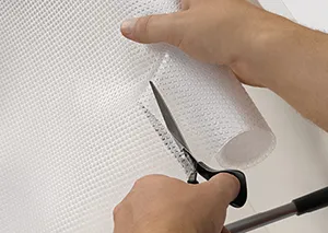 Luftpolsterfolie zuschneiden – Verpackungsmaterial für sicheren Versand Hand schneidet Luftpolsterfolie mit Schere zum Verpacken von Produkten