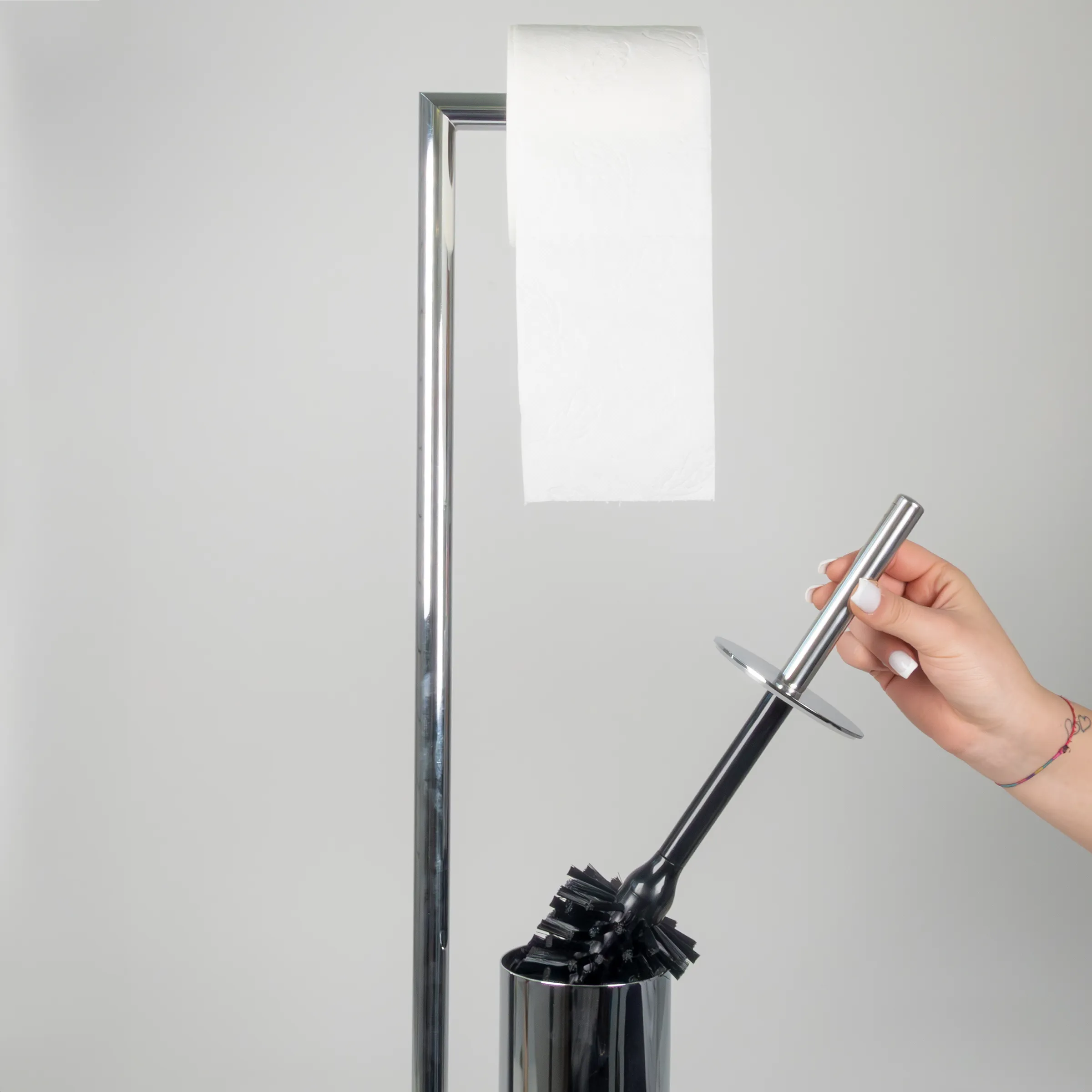Toilettenbürste mit Edelstahl-Halterung - WC-Garnitur Set Hand hält Toilettenbürste mit Halterung aus Edelstahl vor weißem Hintergrund mit Papierhandtuchhalter