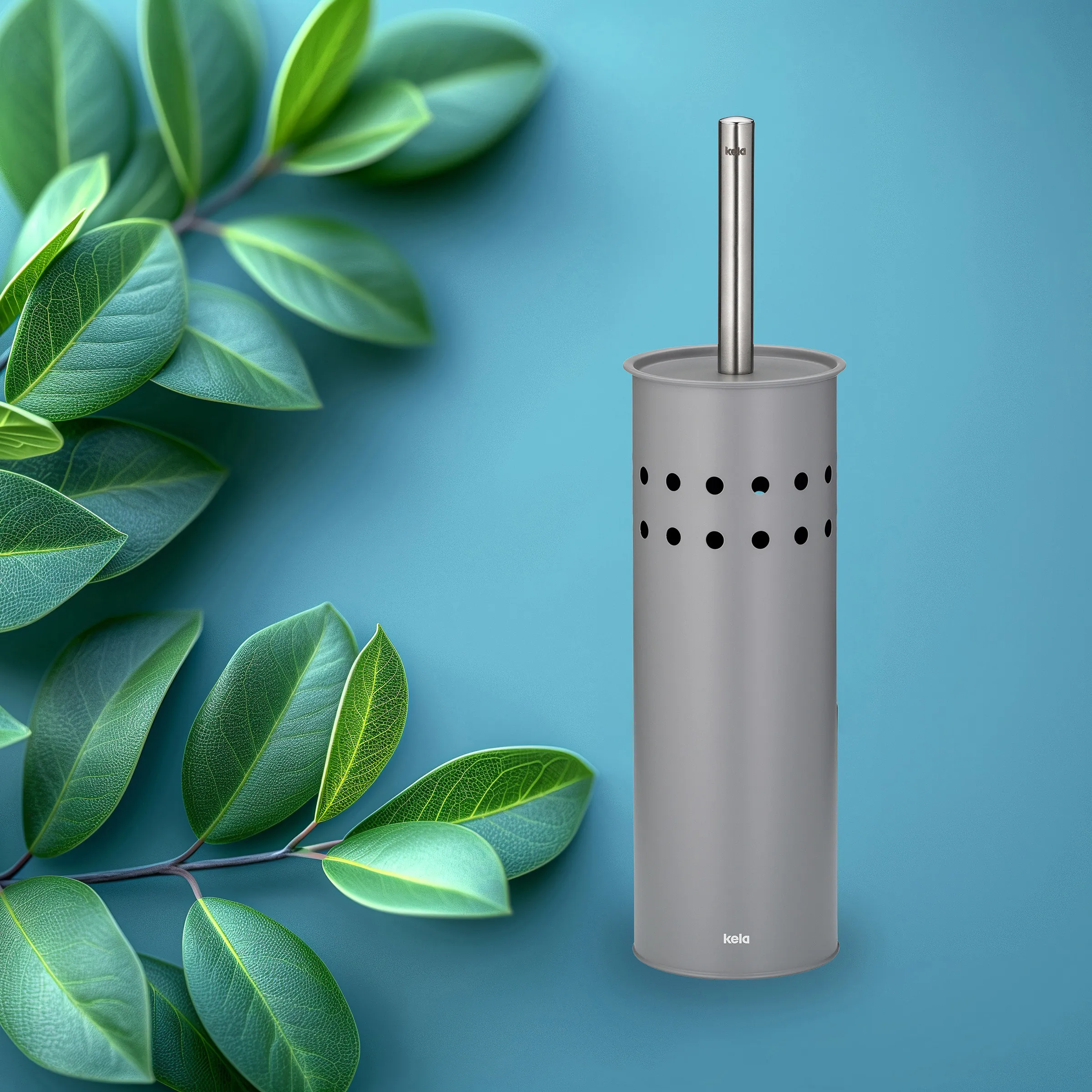 Kela Toilettenbürste Grau mit Lochdesign - Modernes WC-Bürstengarnitur Set Graue Kela Toilettenbürste mit Lochdesign und Metallgriff auf blauem Hintergrund mit grünen Blättern