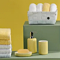 Badezimmer-Set mit gelben Accessoires, Handtüchern und weißen Waschlappen in grauer Aufbewahrungsbox