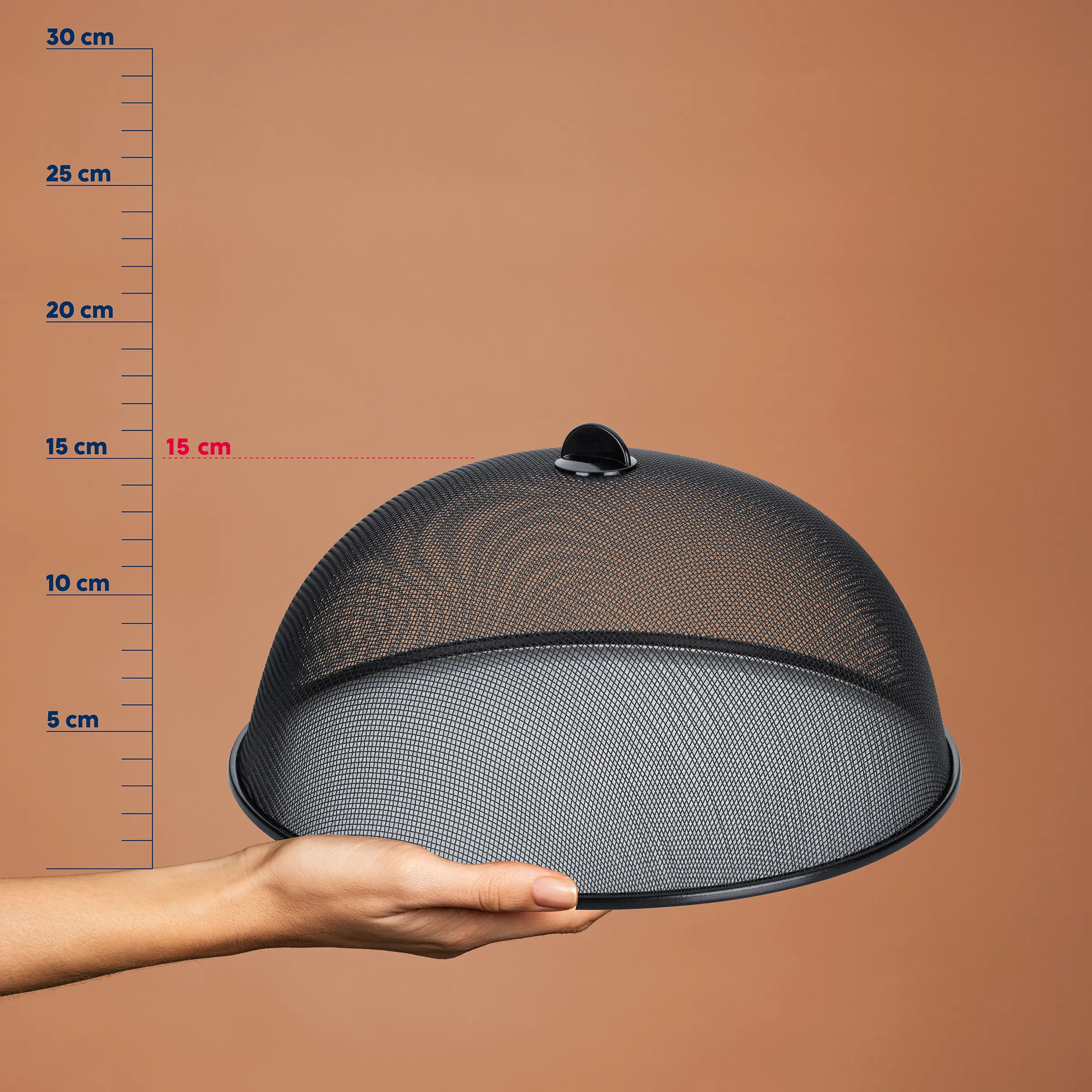 Fliegenhaube Netzgewebe - Lebensmittelschutz Schwarze Fliegenhaube mit Netzgewebe wird in einer Hand gehalten, vor einer Messskala von 0-30 cm. Breite etwa 15 cm.