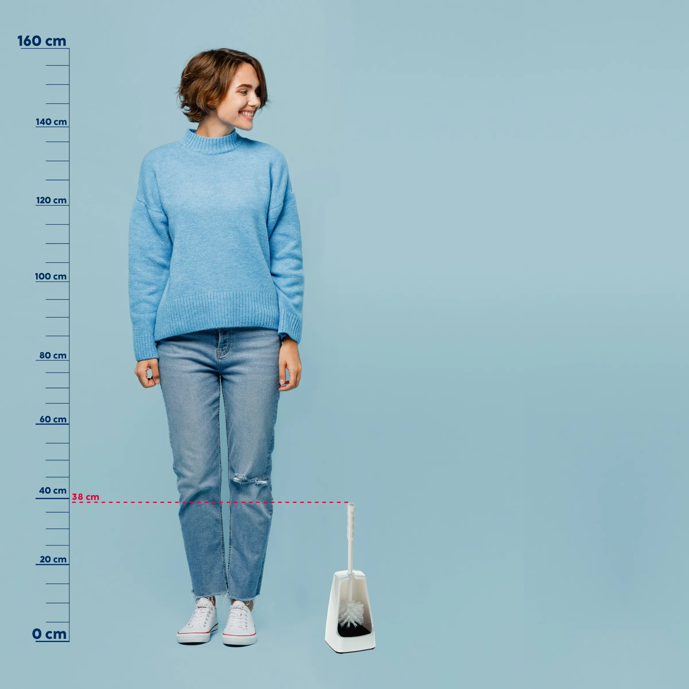Strickpullover Damen hellblau - Größenvergleich Frau in hellblauem Strickpullover und zerrissener Jeans steht neben einer weißen Flasche vor blauem Hintergrund