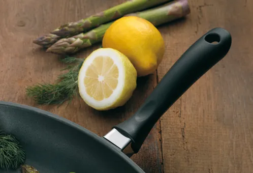 Pfanne mit Spargel und Zitrone - Frische Kochzutaten Kochszene mit schwarzer Pfanne, halbierten Zitronen, frischem Spargel und Dill auf Holzoberfläche