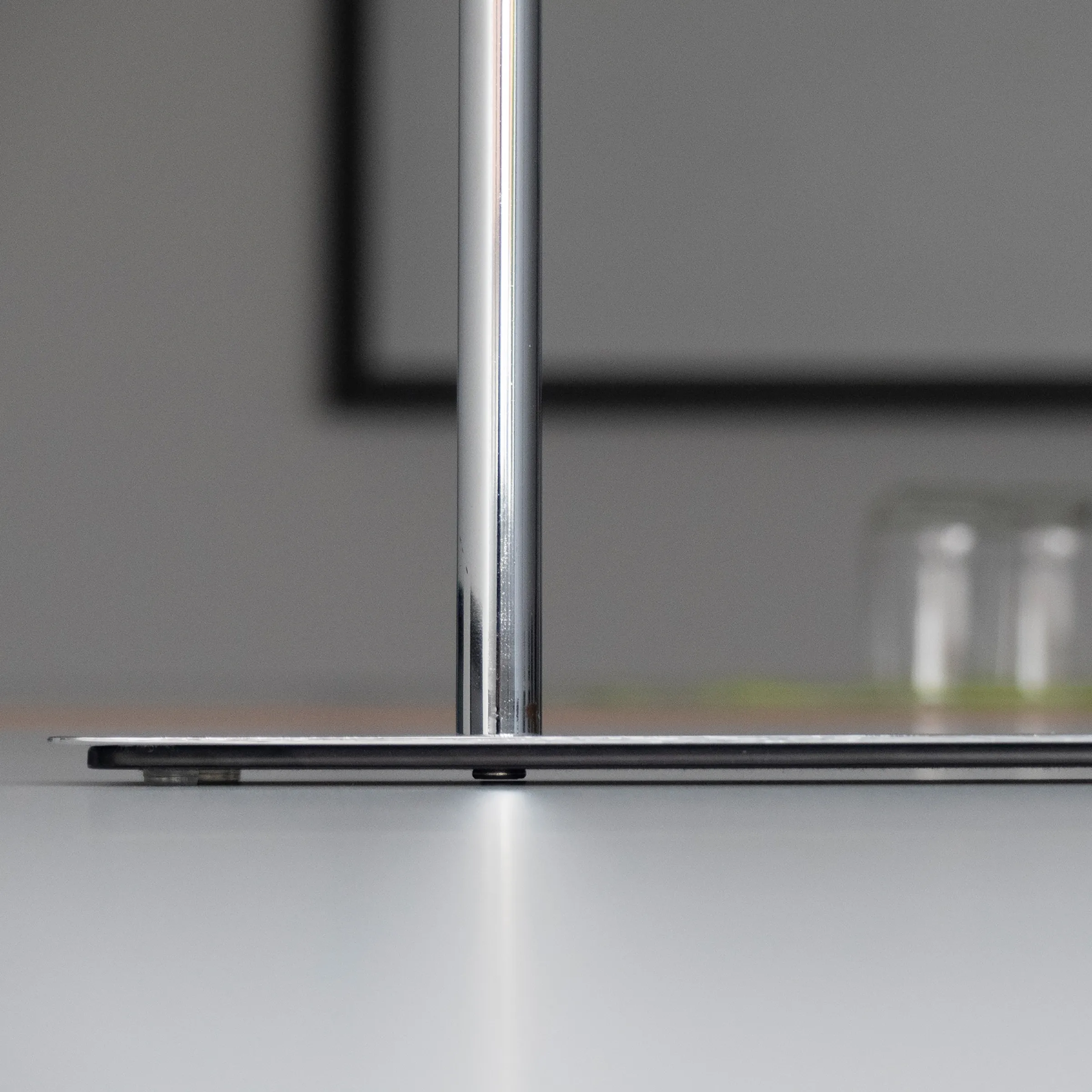 Nahaufnahme einer modernen Glastrennwand mit Aluminiumprofil und Dichtung auf glänzender Oberfläche