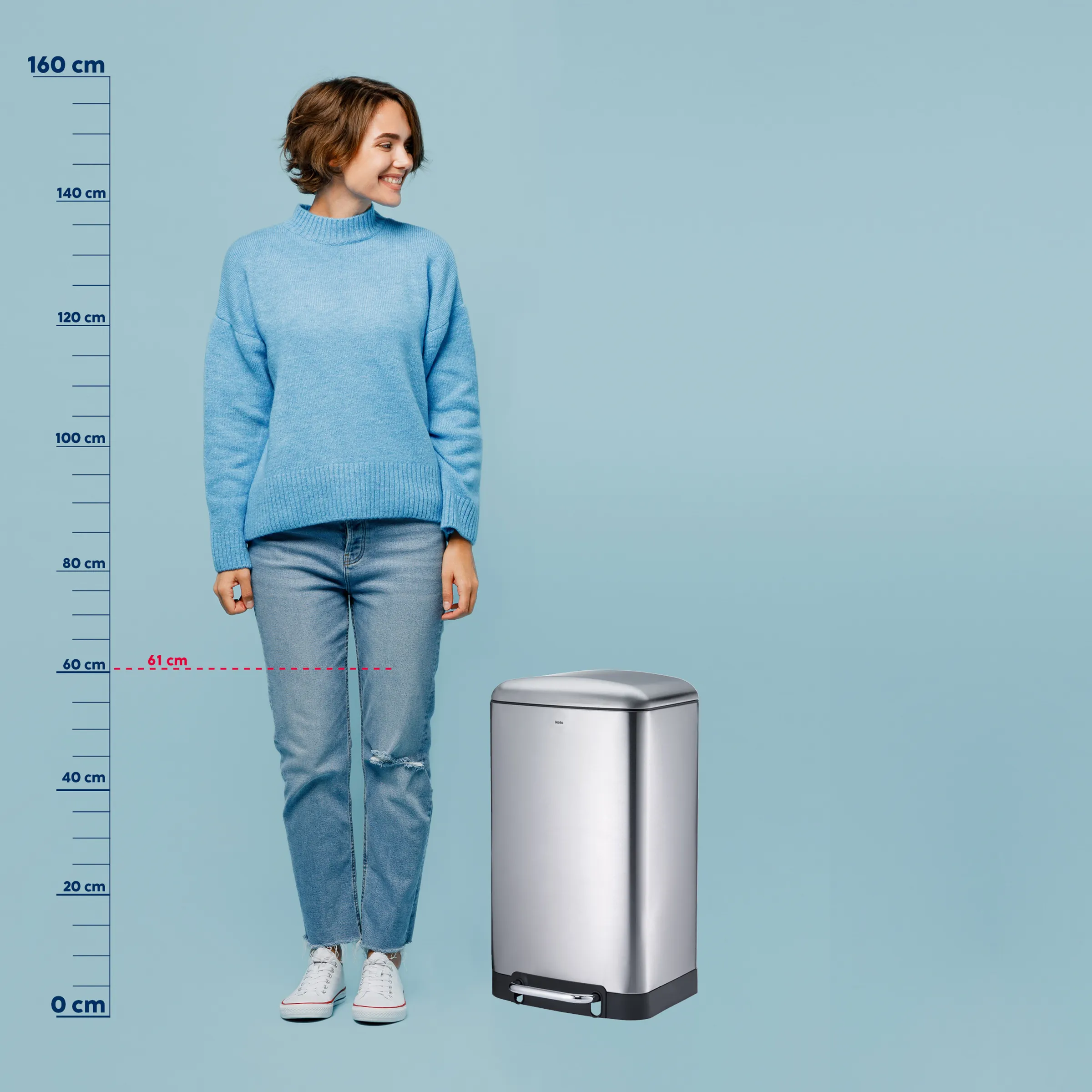 Automatischer Mülleimer mit Sensor - Größenvergleich Frau in blauem Pullover neben silbernem Mülleimer mit Größenvergleich auf blauem Hintergrund