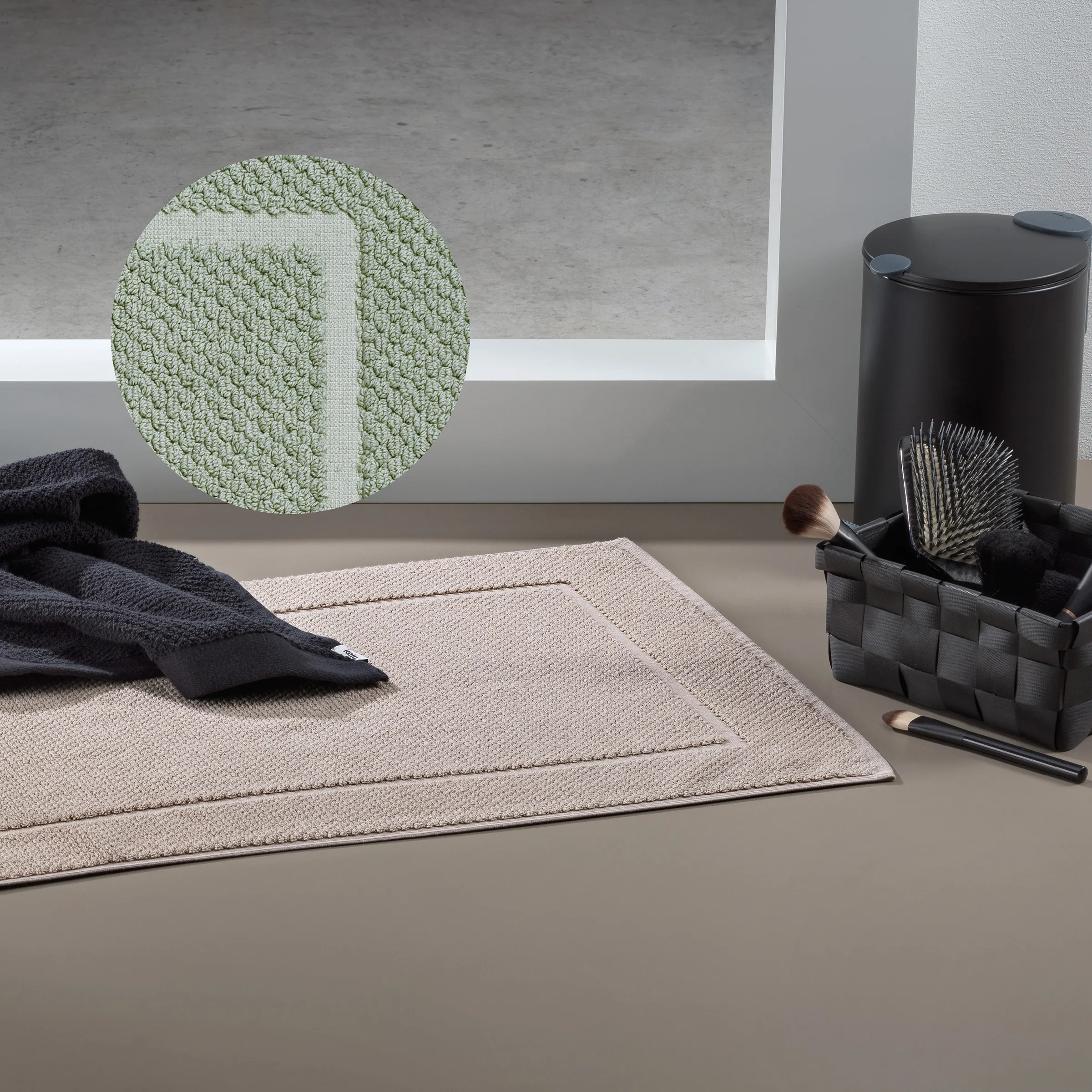 Badezimmer-Accessoires Set mit Badematte, Teppich und Kosmetikutensilien Badezimmer mit beiger Badematte, grünem rundem Teppich, schwarzem Handtuch und Kosmetikkorb