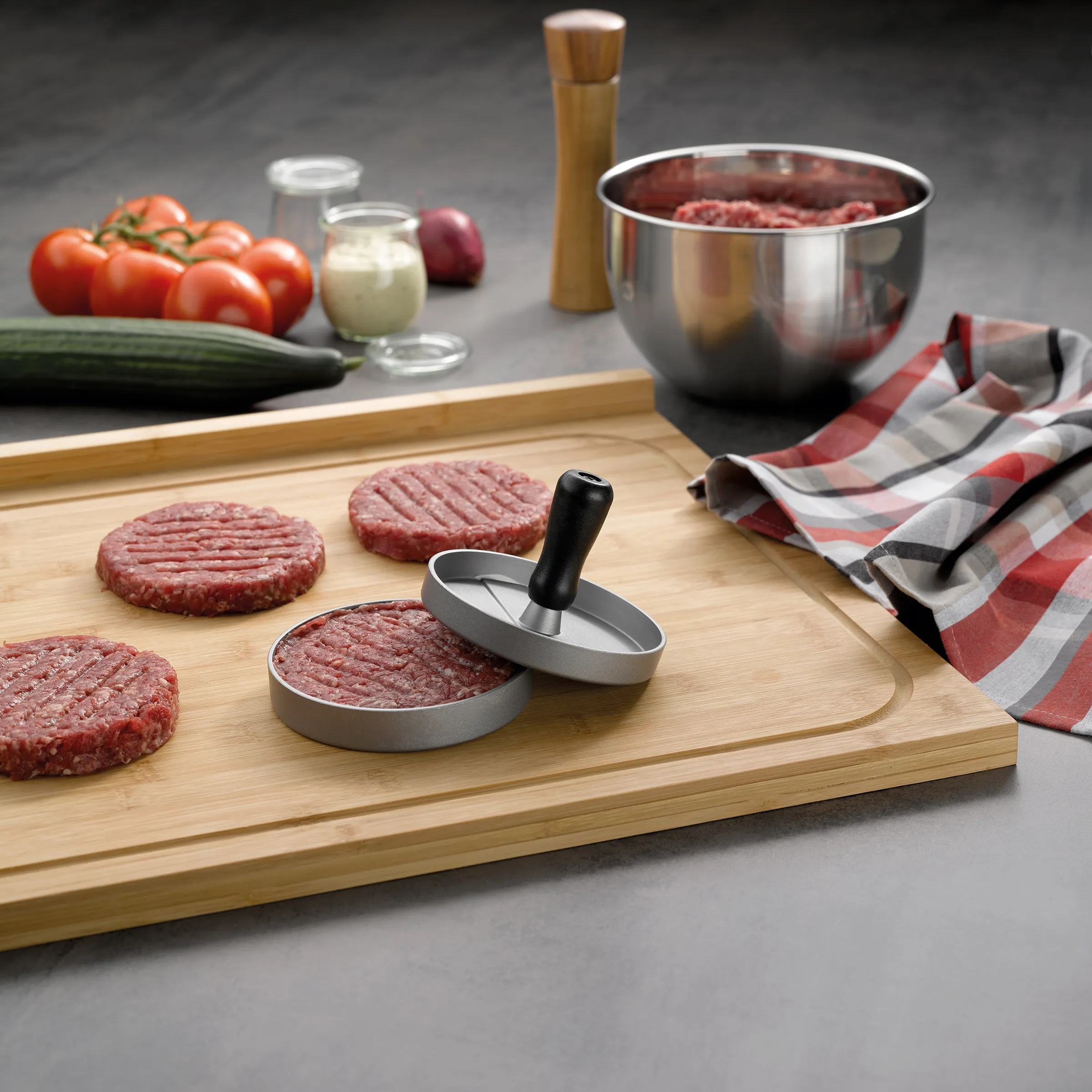 Burgerpresse für perfekte Hamburger-Patties - Hackfleisch-Formpresse Burgerpresse mit rohen Hamburger-Patties auf Holzbrett, Hackfleisch in Schüssel und frischen Zutaten