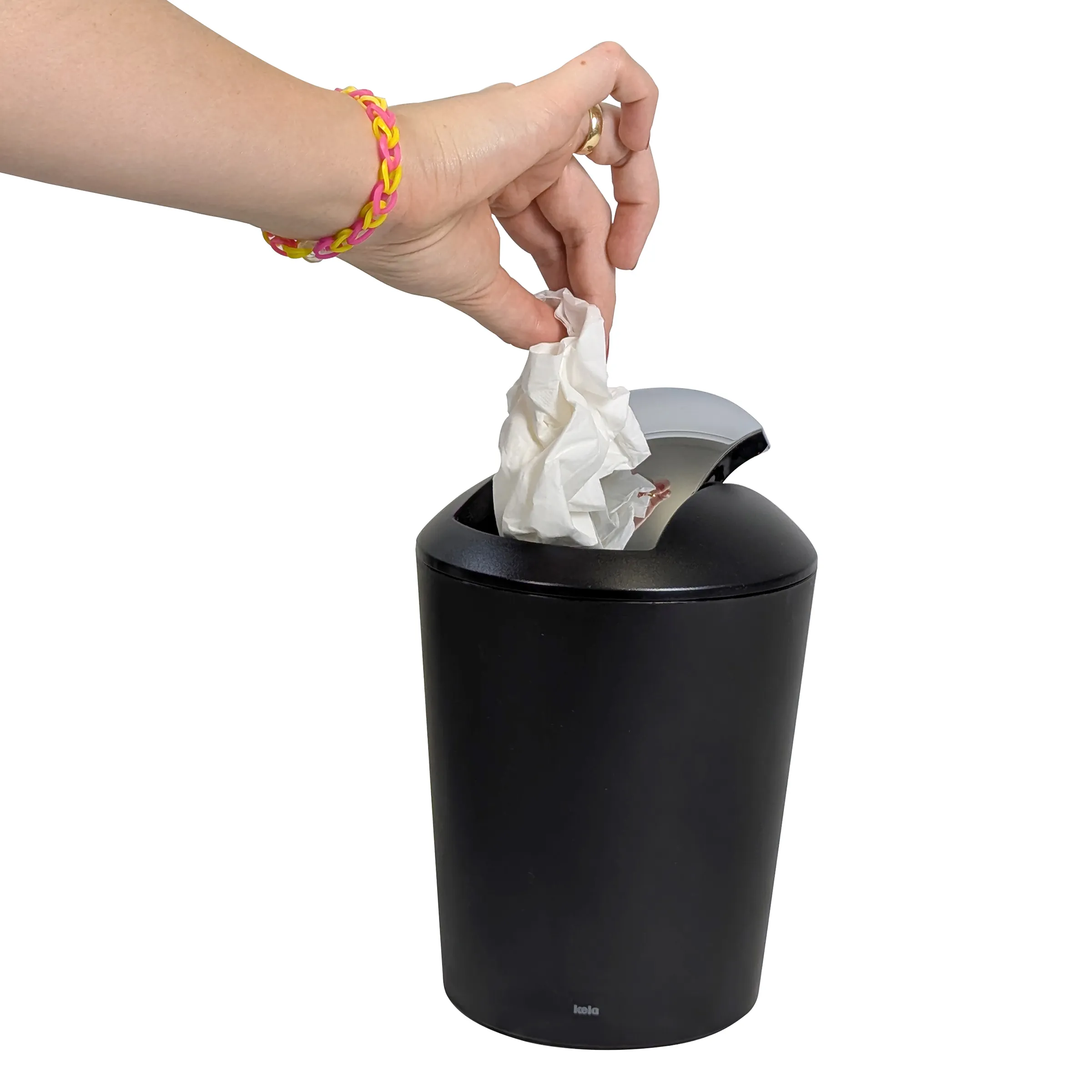 Hand wirft zerknülltes Papier in schwarzen Mülleimer mit Schwingdeckel