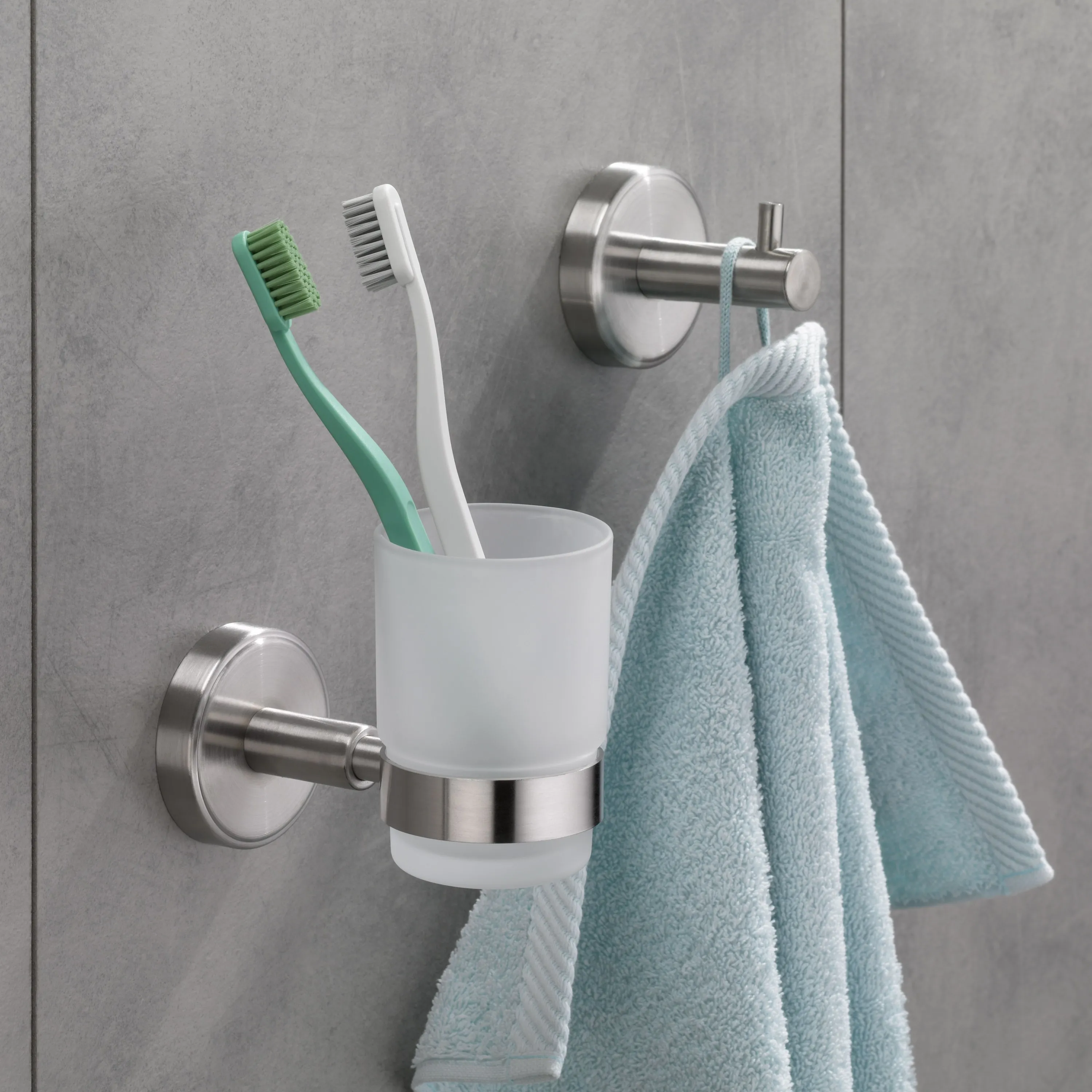 Bathroom Accessories Set with Towel Holder and Toothbrush Cup Bathroom wall set with silver towel holder, white toothbrush cup, and green and white toothbrushes on gray tile