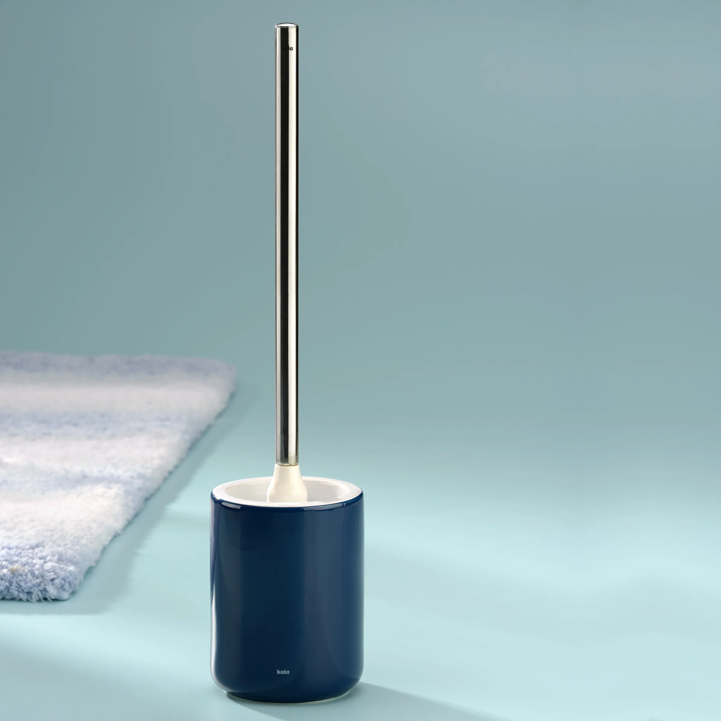Toilettenbürste mit Keramikhalter in Blau und Edelstahlgriff für modernes Badezimmer Blaue Toilettenbürste mit Edelstahlstiel und Keramikhalter auf mintfarbenem Hintergrund mit Handtuch