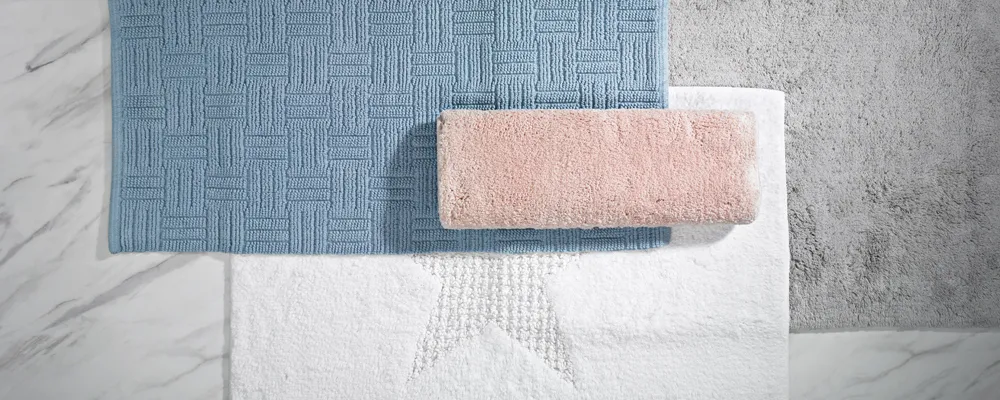 Premium Handtücher Set – Blau, Rosa, Weiß und Grau Flache Anordnung von vier Handtüchern in Blau, Rosa, Weiß und Grau auf Marmor- und Betonfliesen