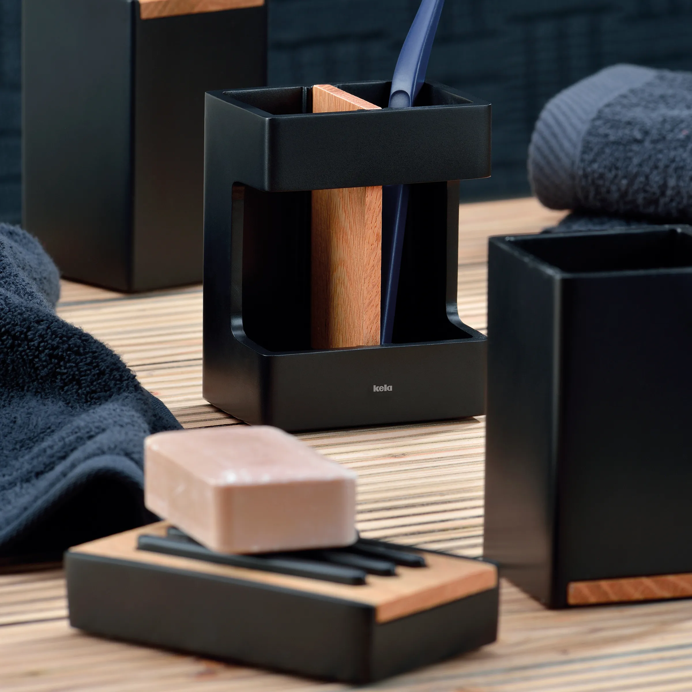 Premium Badezimmer Accessoires Set - Moderne schwarze Design Kollektion Schwarze Designbadezimmerzubehöraccessoires mit Holzakzenten auf hellem Holzboden, einschließlich Seifenspender und Behälter