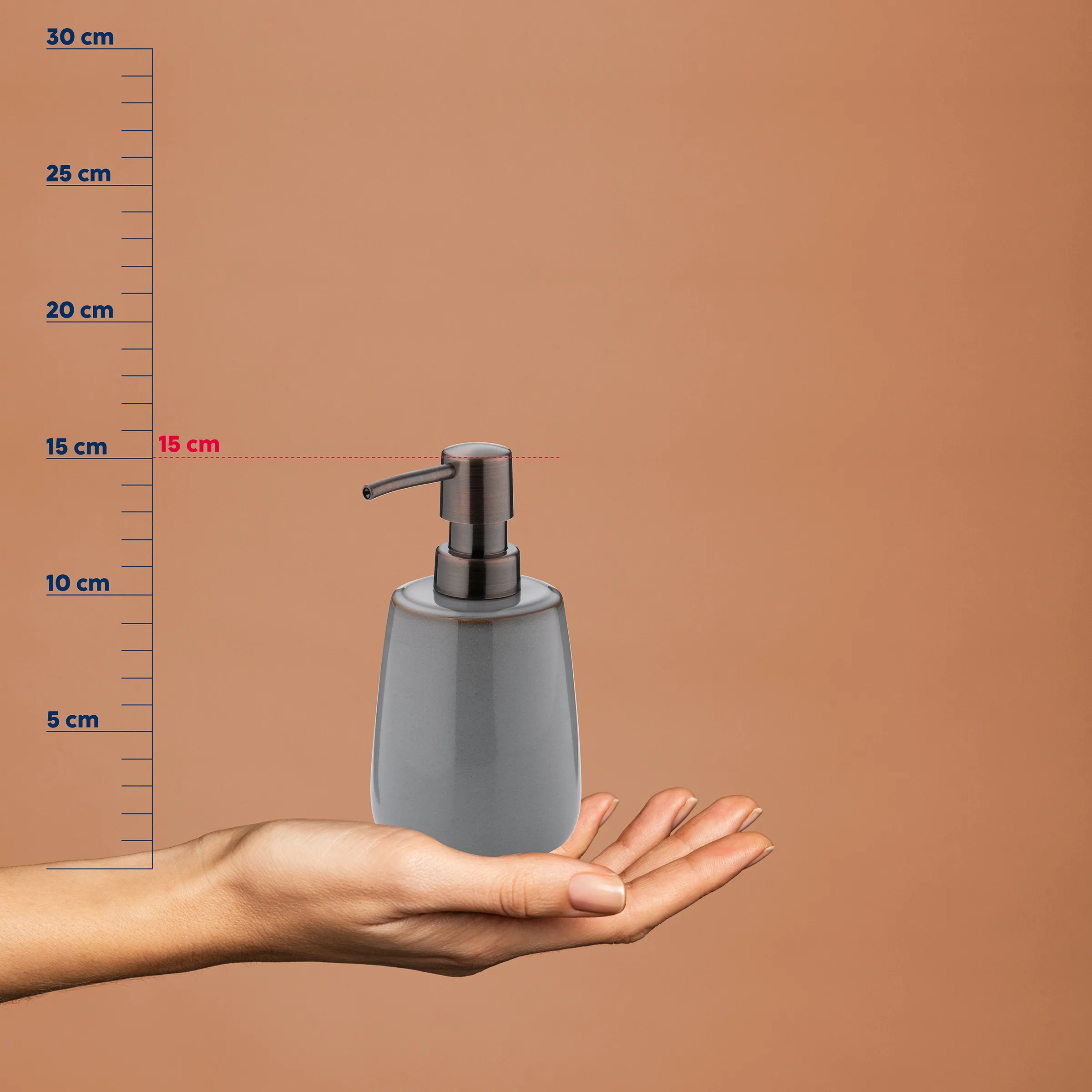 Grauer Seifenspender mit Metallpumpe auf Hand, Größenvergleich mit Lineal zeigt 15 cm Höhe