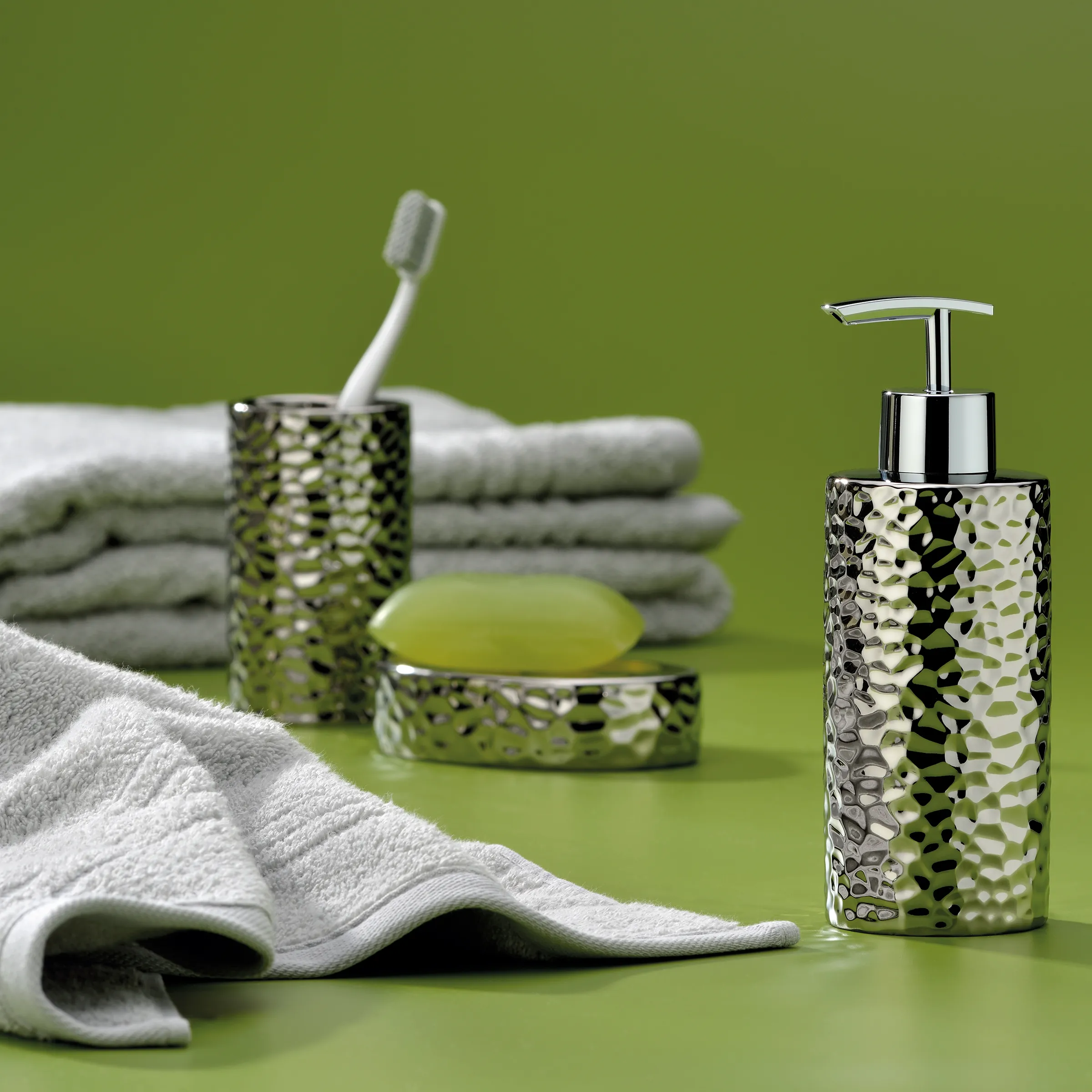 Grünes Badezimmer-Set mit strukturierter Oberfläche: Seifenspender, Zahnbürstenhalter, Seifenschale, Handtücher und Zahnbürste