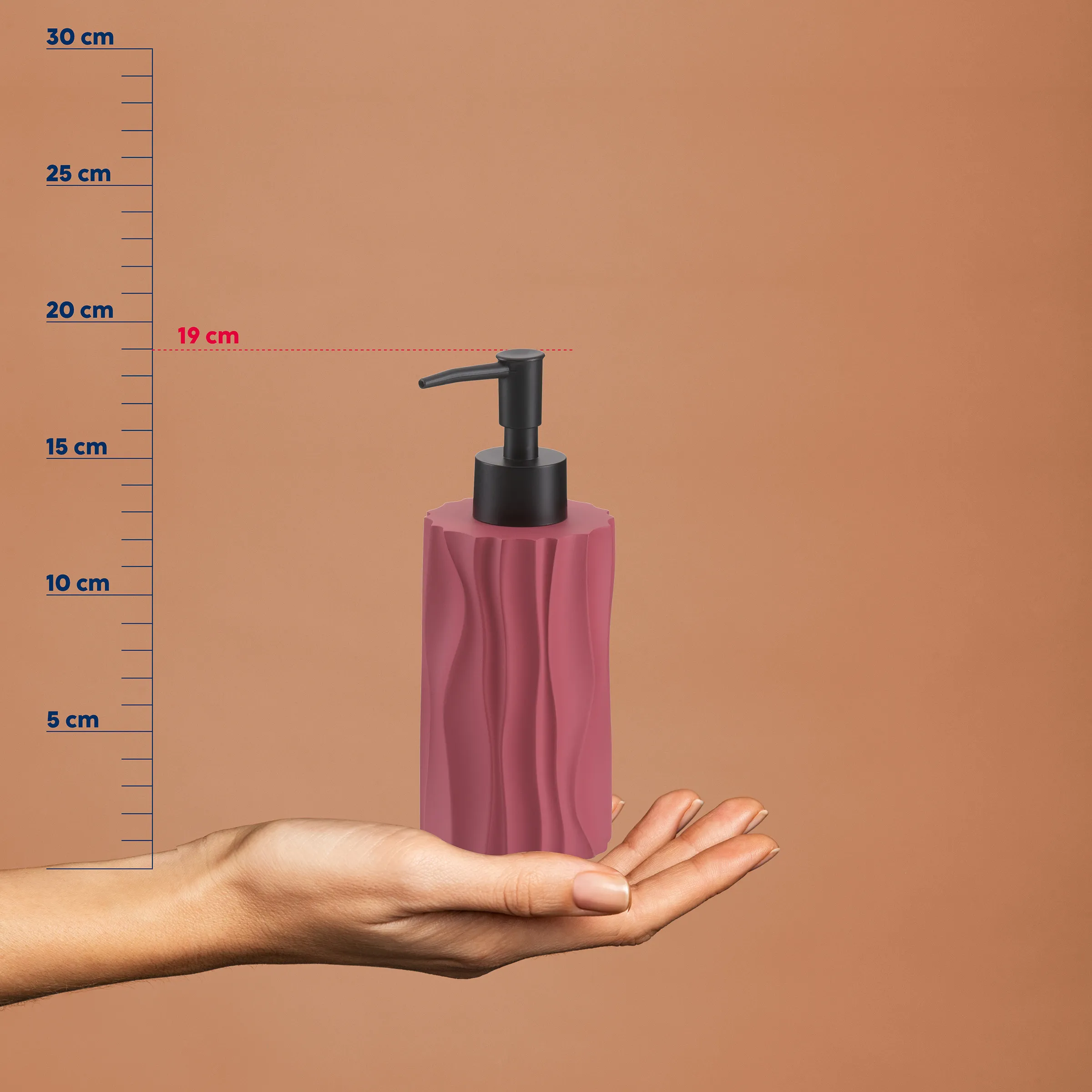Rosa Seifenspender mit schwarzem Pumpenkopf in einer Hand, Größenvergleich zeigt etwa 20 cm Höhe