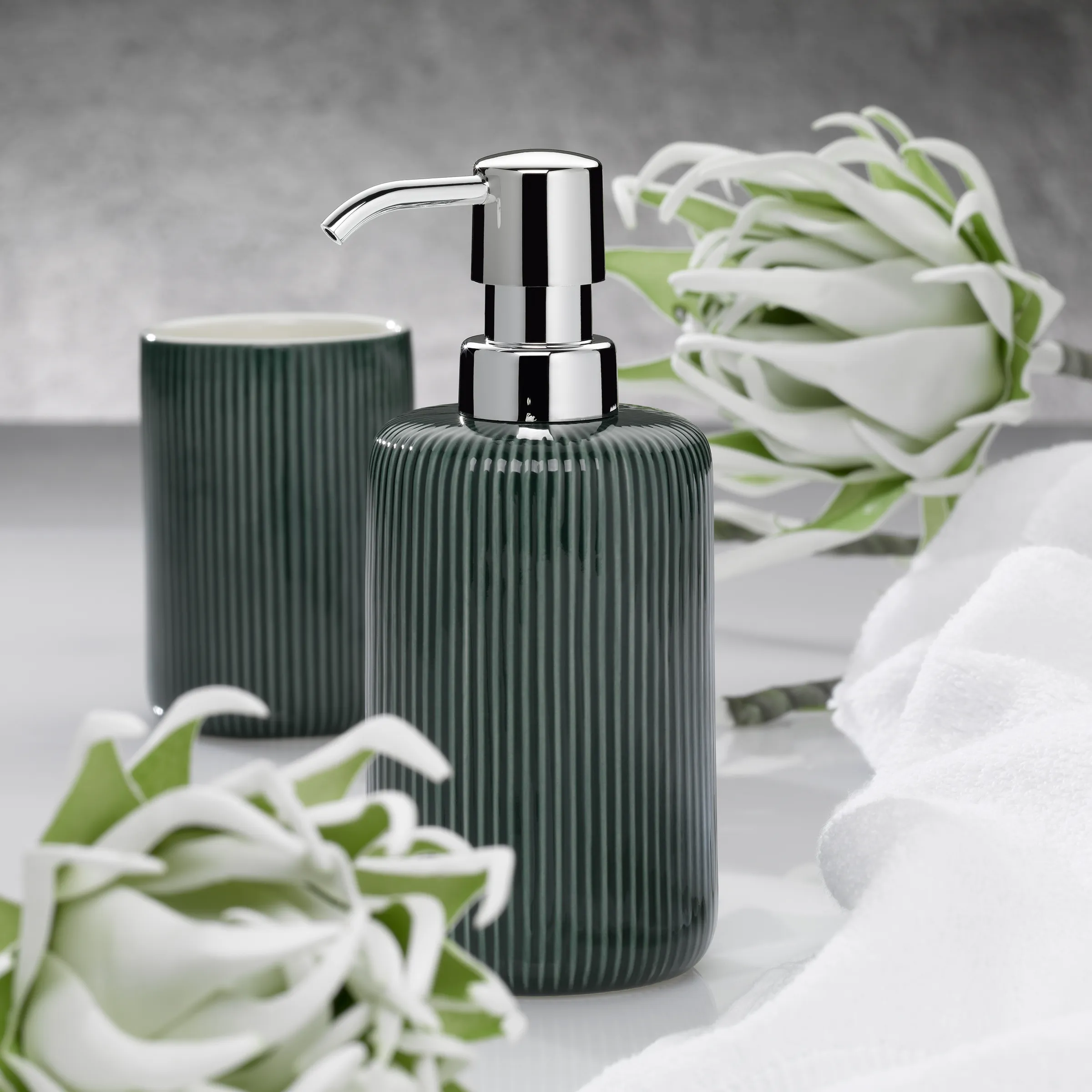 Seifenspender und Bad Accessoires Set grün Grüne gerillte Seifenspender und Zahnputzbecher mit Flores-Dekoration auf grauem Hintergrund
