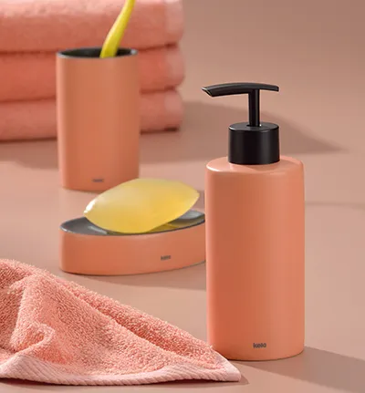 Badezimmer-Set aus korallenrosa Keramik mit Seifenspender, Seifenschale, Zahnbürstebecher und rosa Handtuch