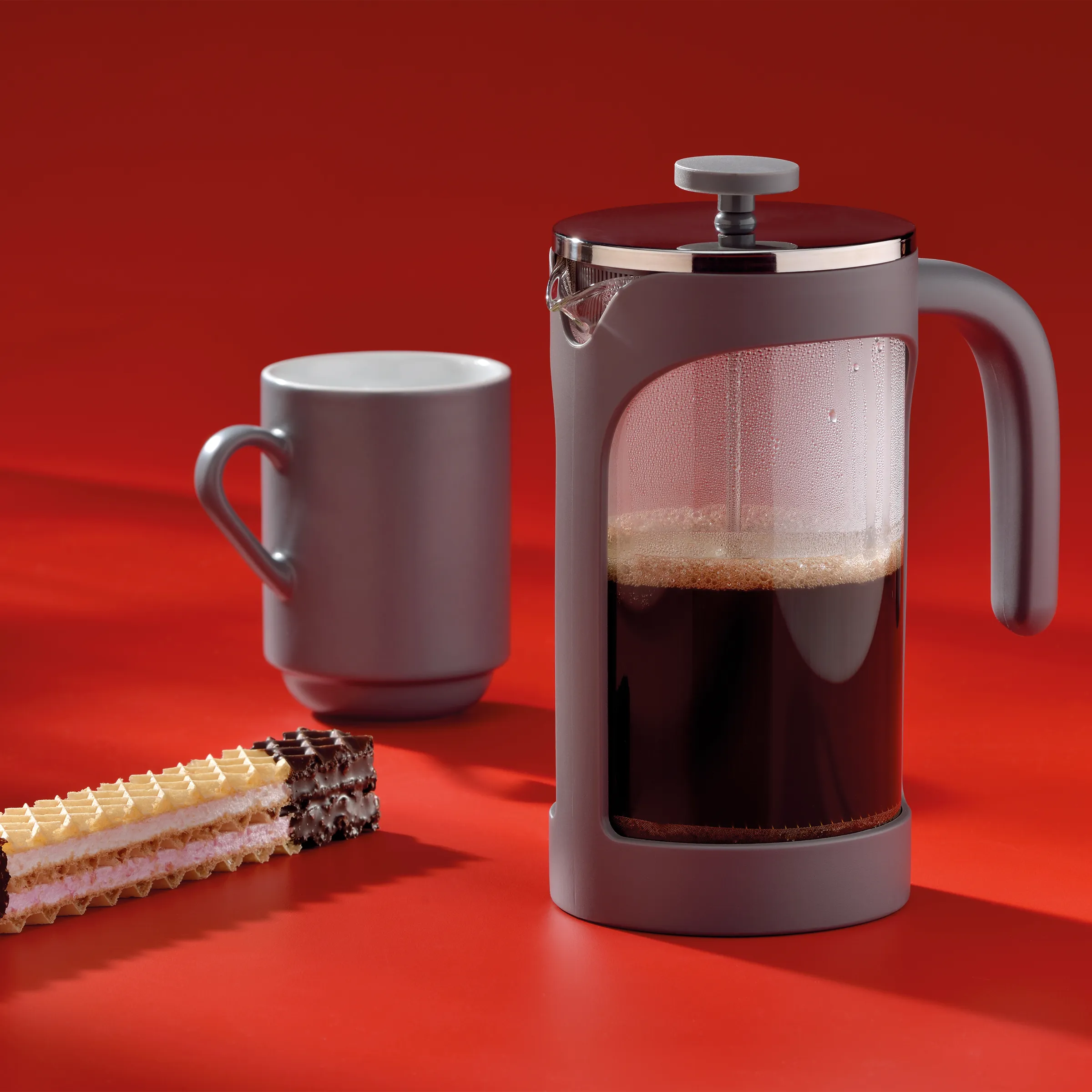 French Press Kaffeebereiter - Kaffee zubereiten leicht gemacht French Press Kaffeebereiter mit Kaffee neben leerer Tasse und Schokoladenkuchen auf rotem Hintergrund